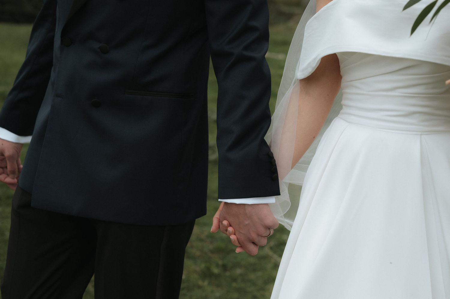 Wedding ceremony detail showing formal attire and joined hands.