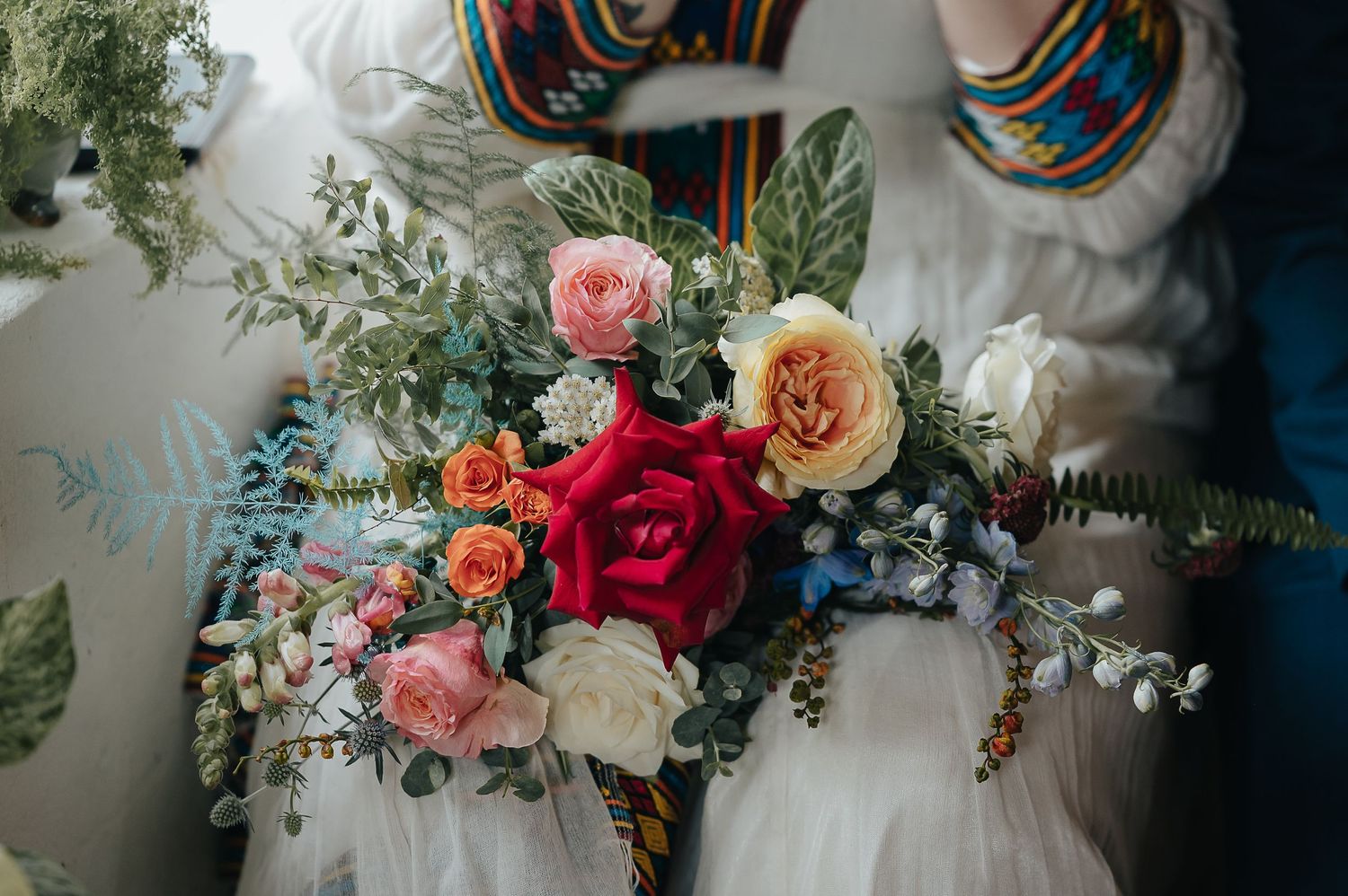 Vibrant wedding bouquet featuring pink and red roses with mixed greenery.