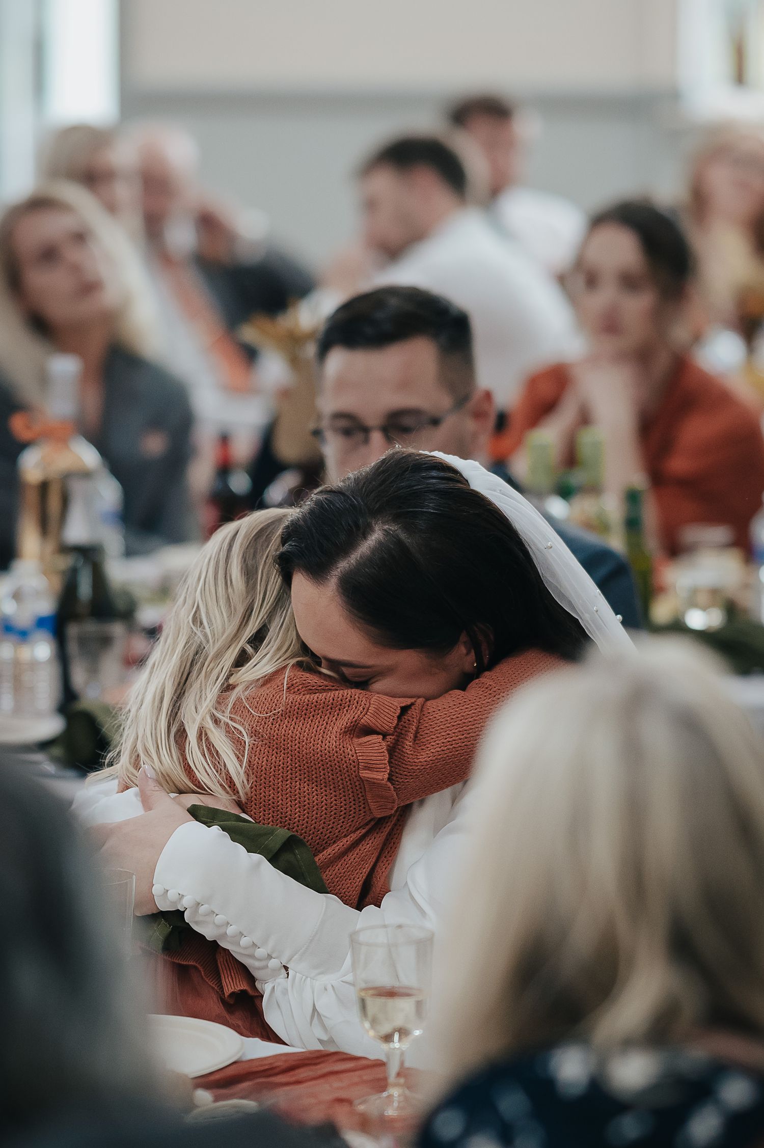 Intimate embrace shared during wedding reception with string lights and party decorations visible.