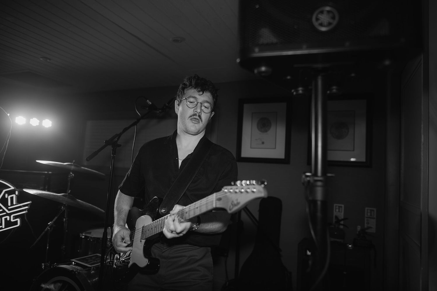 A spotlight illuminates a guitarist performing passionately on stage during a live concert performance.