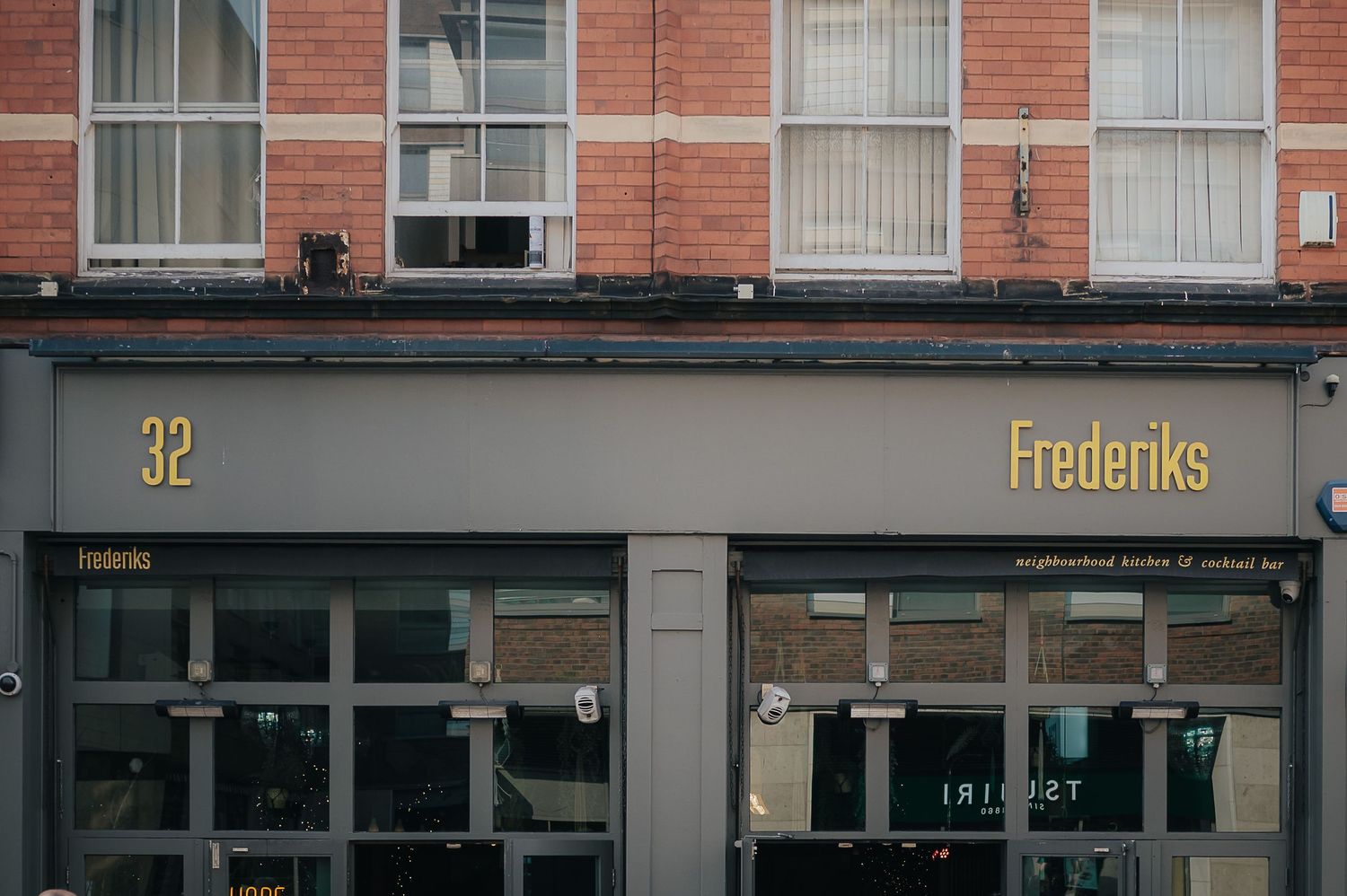 The storefront of Frederiks establishment with gold lettering on grey facade.