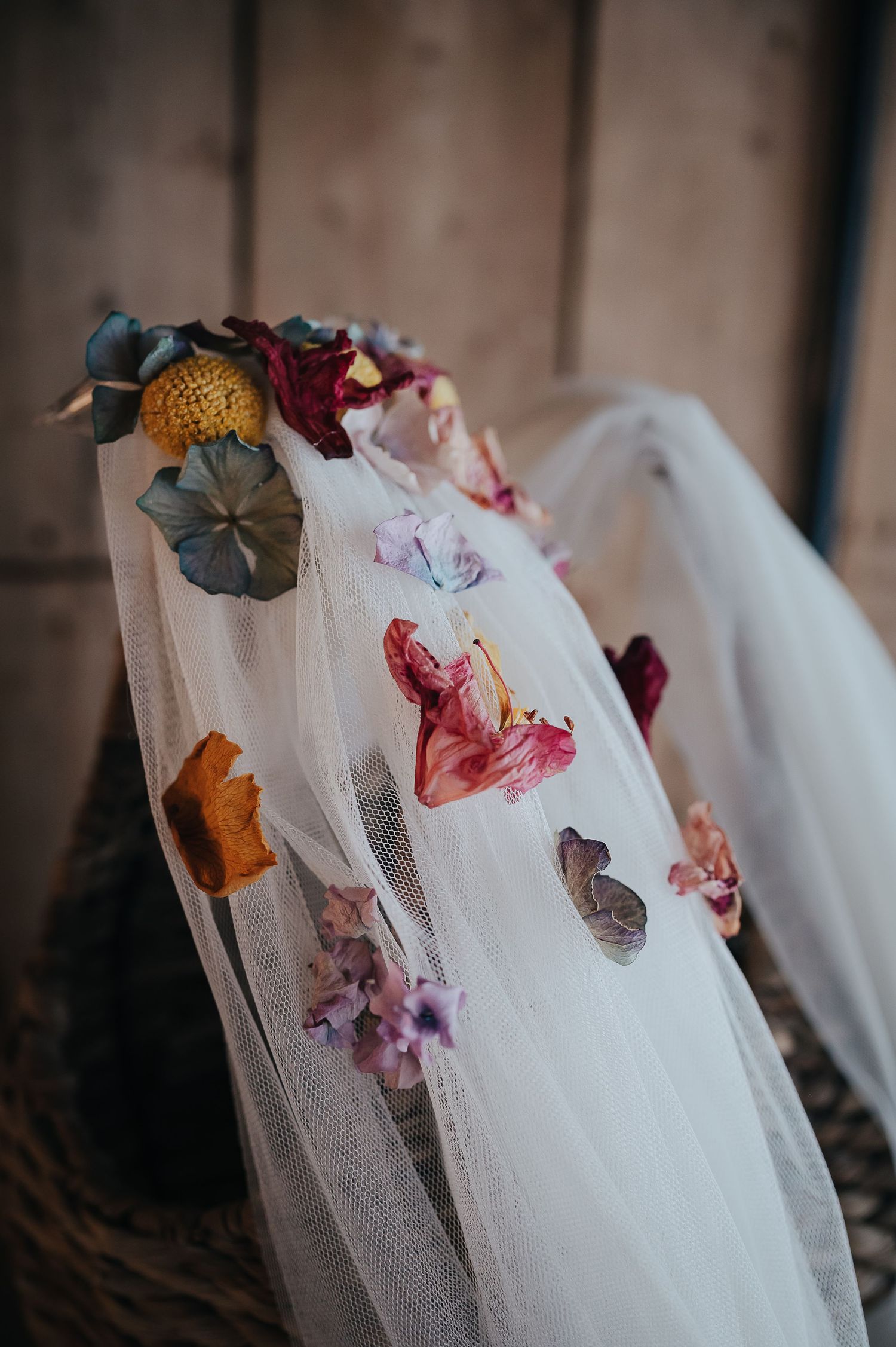 Delicate floral details adorn white tulle wedding veil in closeup.