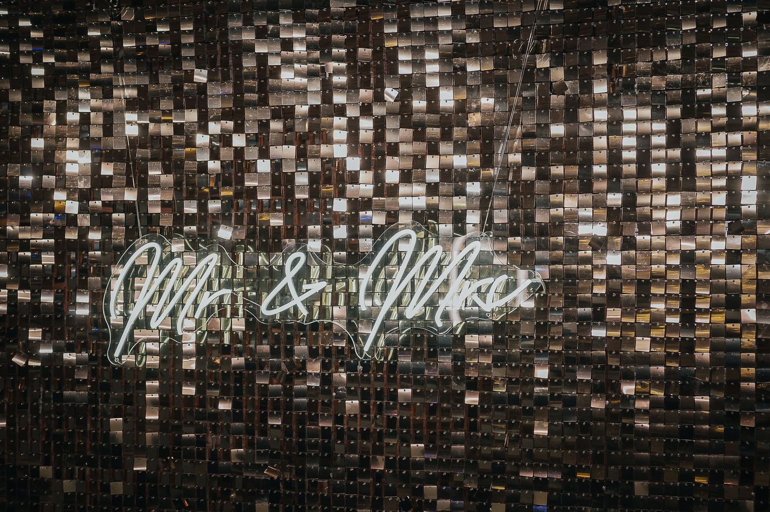 A neon 'Mr & Mrs' sign illuminates against a dark tiled wall.