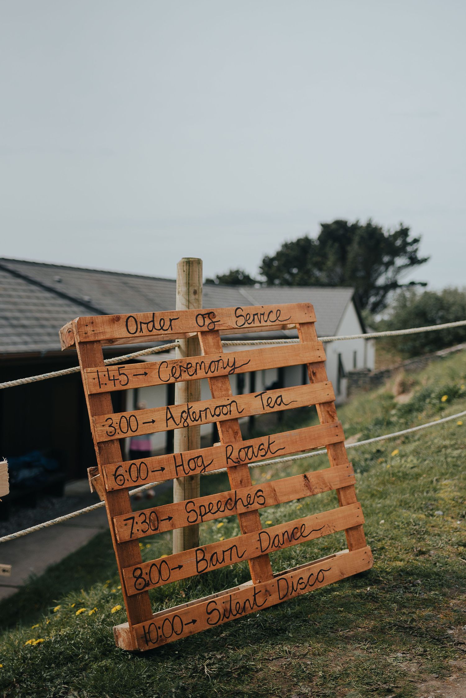 A wooden pallet displays the wedding day timeline and schedule of events.