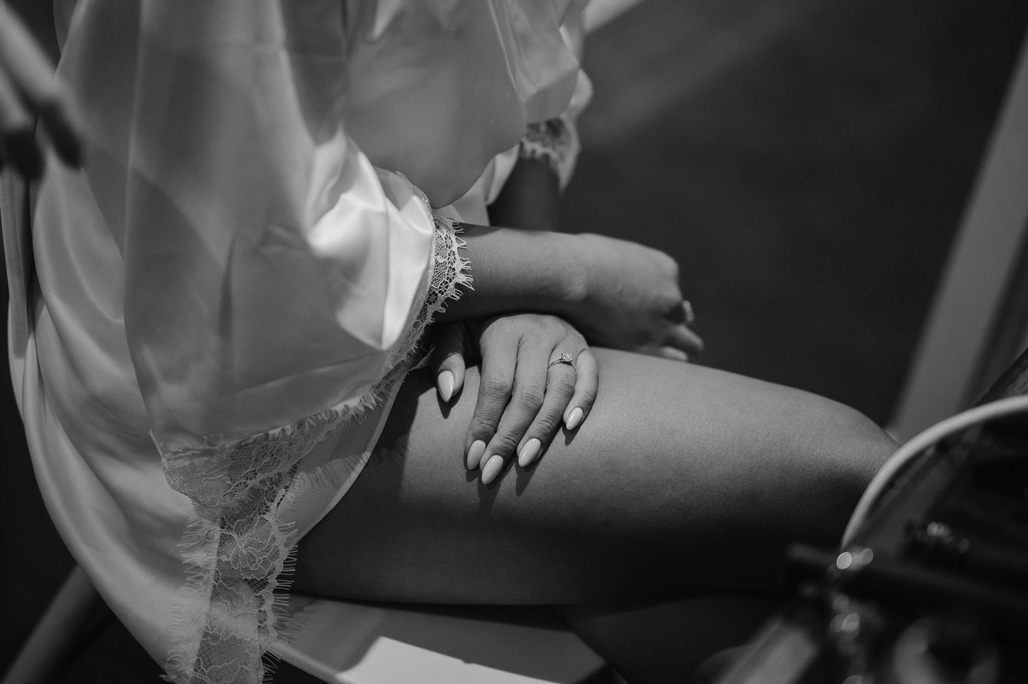 Close-up black and white photo of hands resting on lace fabric.