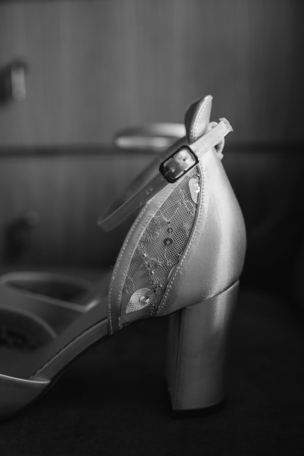 Close-up of vintage style bridal shoe with delicate lace detail and ankle strap.