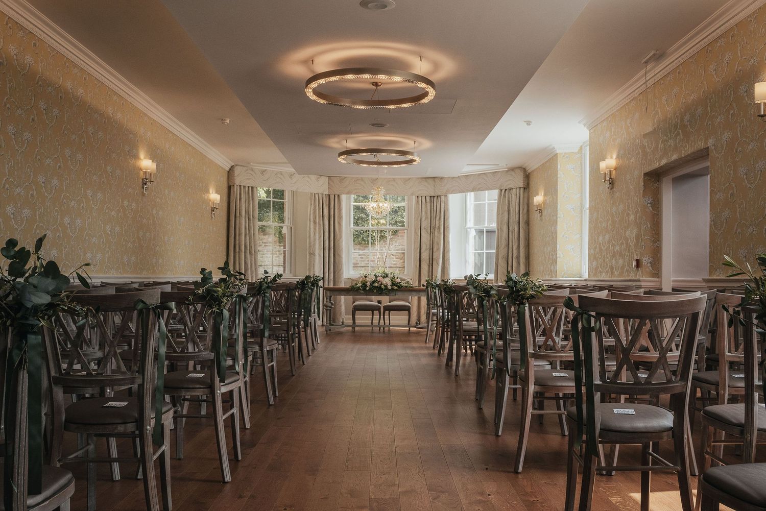 An elegant wedding reception venue with empty chairs and circular ceiling lights.