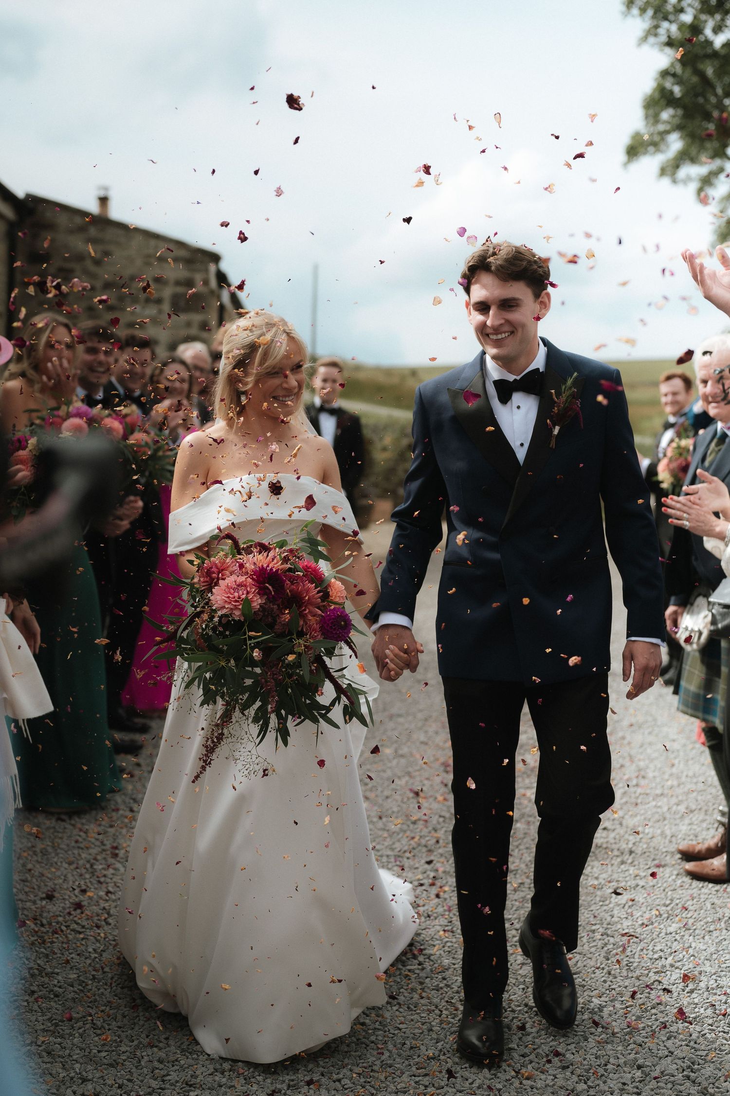 Newlyweds walking through a shower of rose petals after their wedding ceremony.Blackton Grange Wedding. Luke Hassall Photography.
