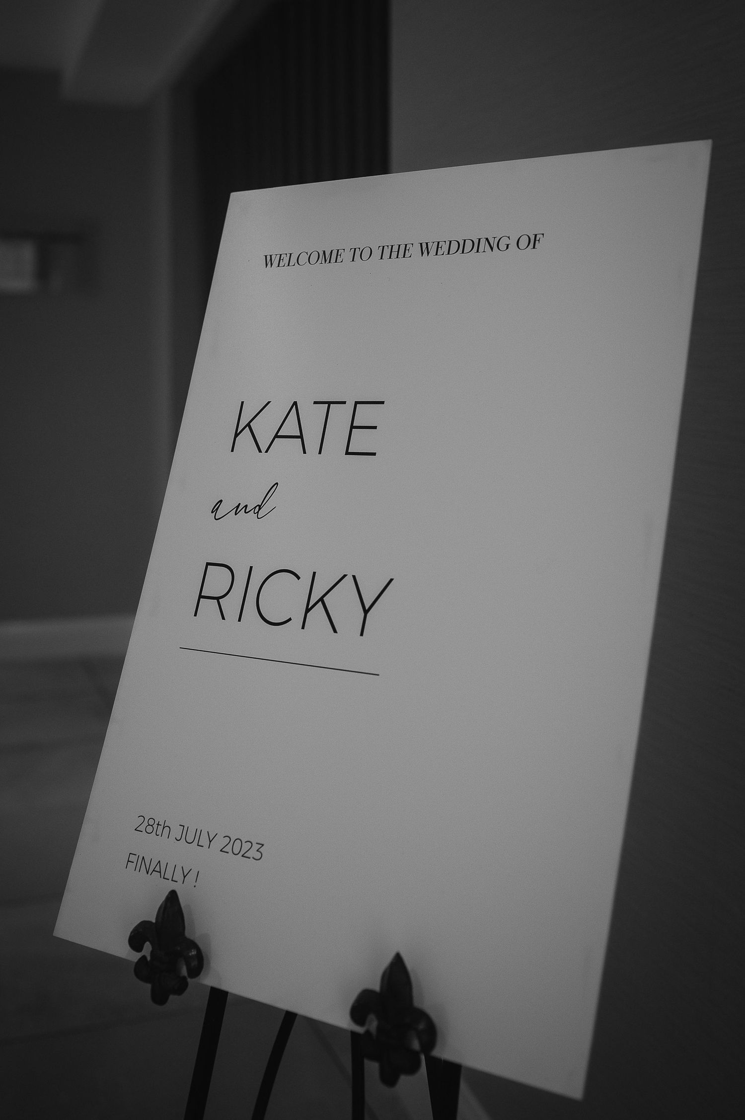 A minimal black and white wedding welcome sign displayed on an easel.