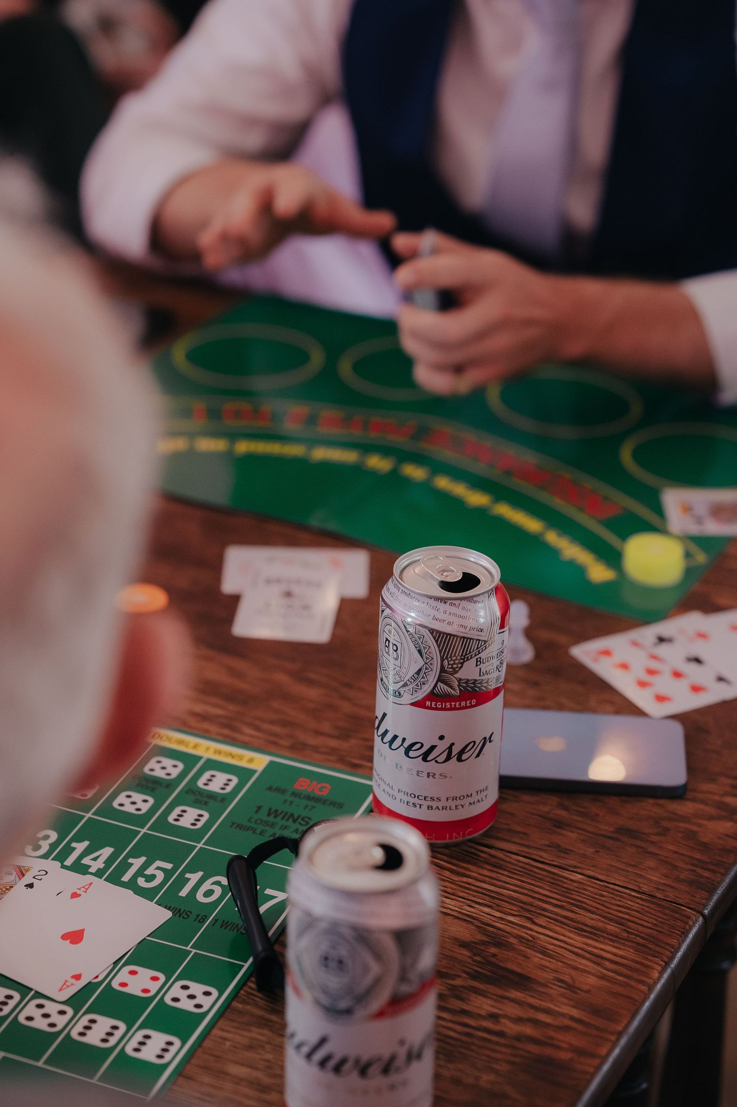 Budweiser beer cans on a casino table with cards and betting layout.