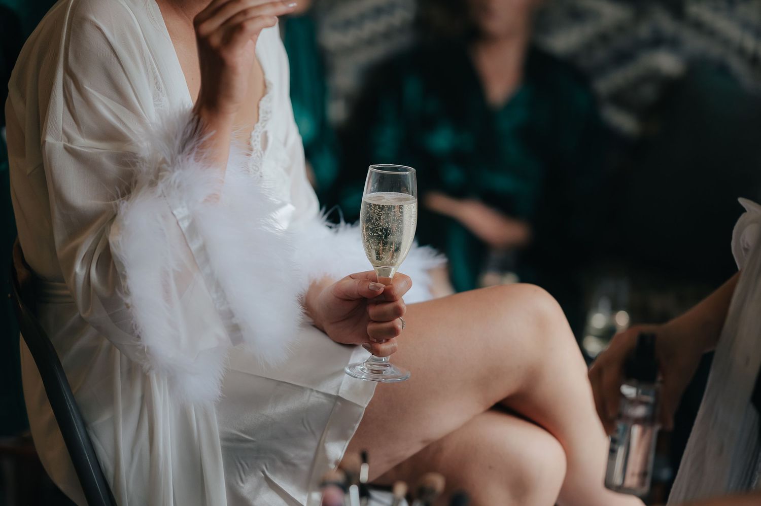Close-up of champagne glass held during wedding preparation.