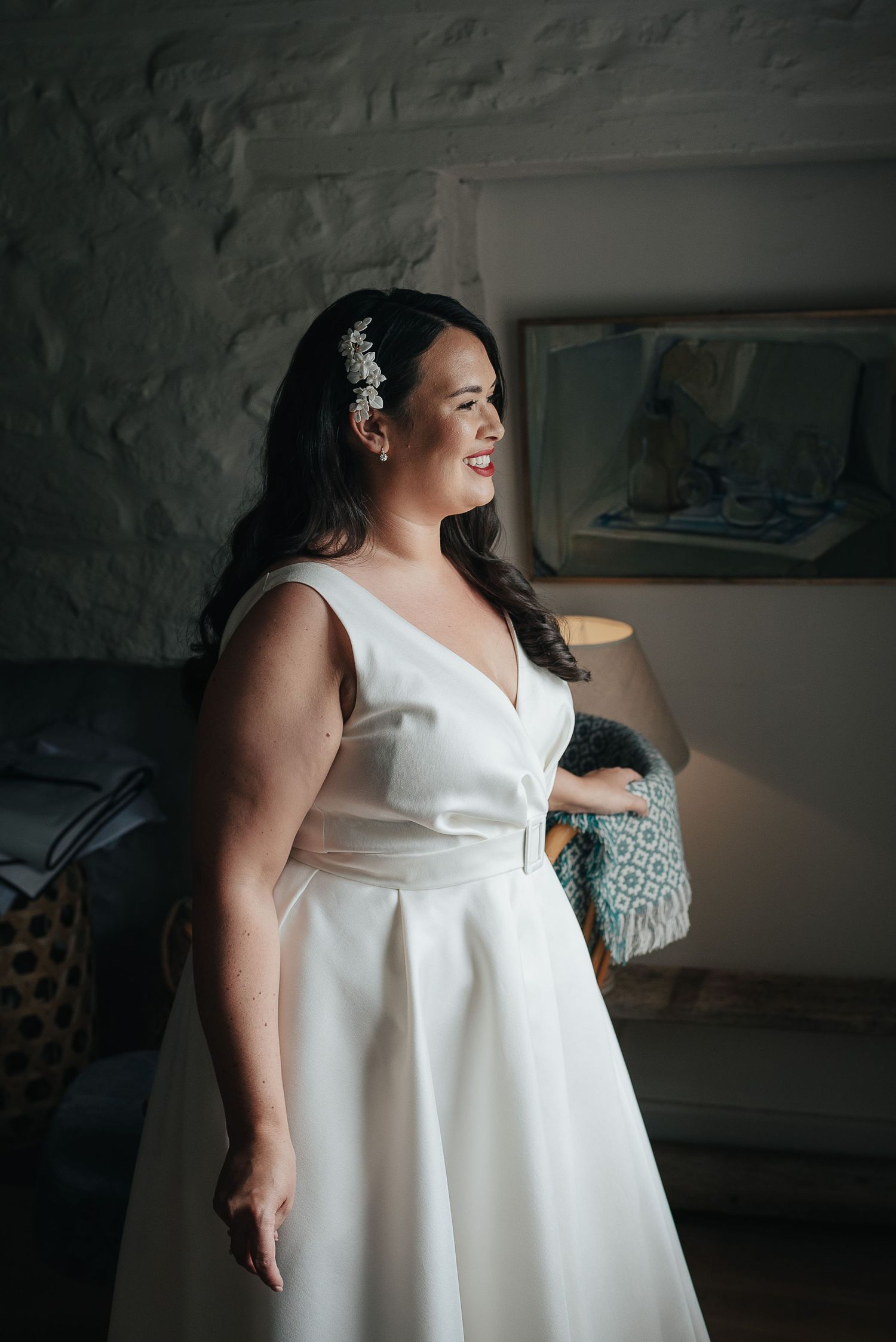 Person in classic white wedding dress standing in softly lit interior.