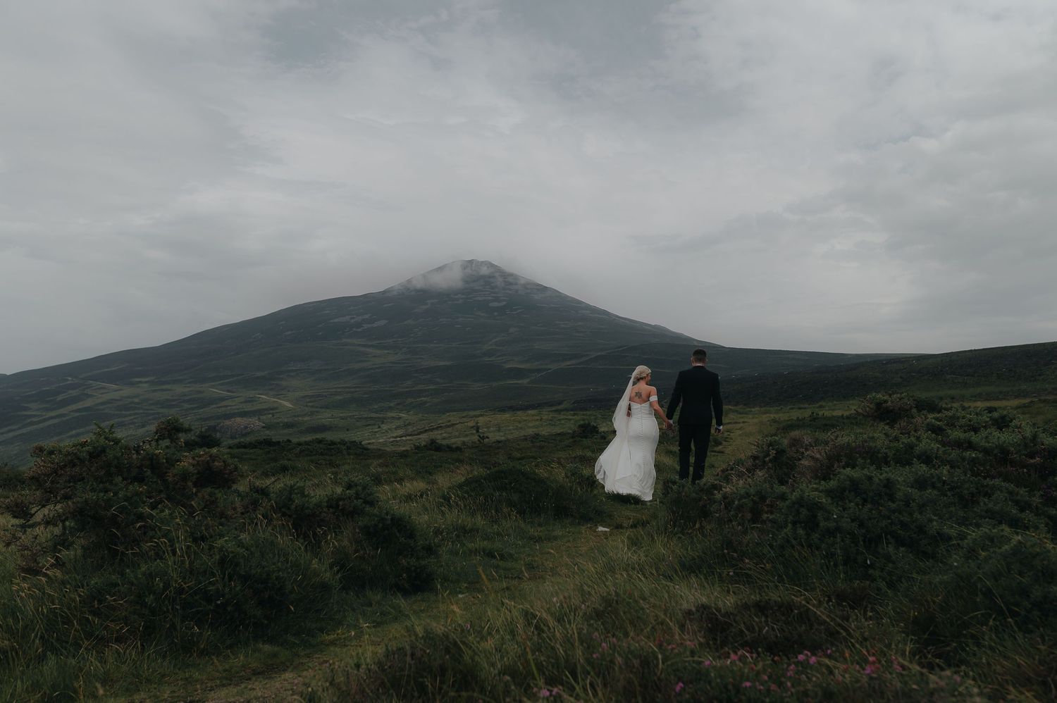 Rolling green hills and mountains create a dramatic landscape under moody skies.