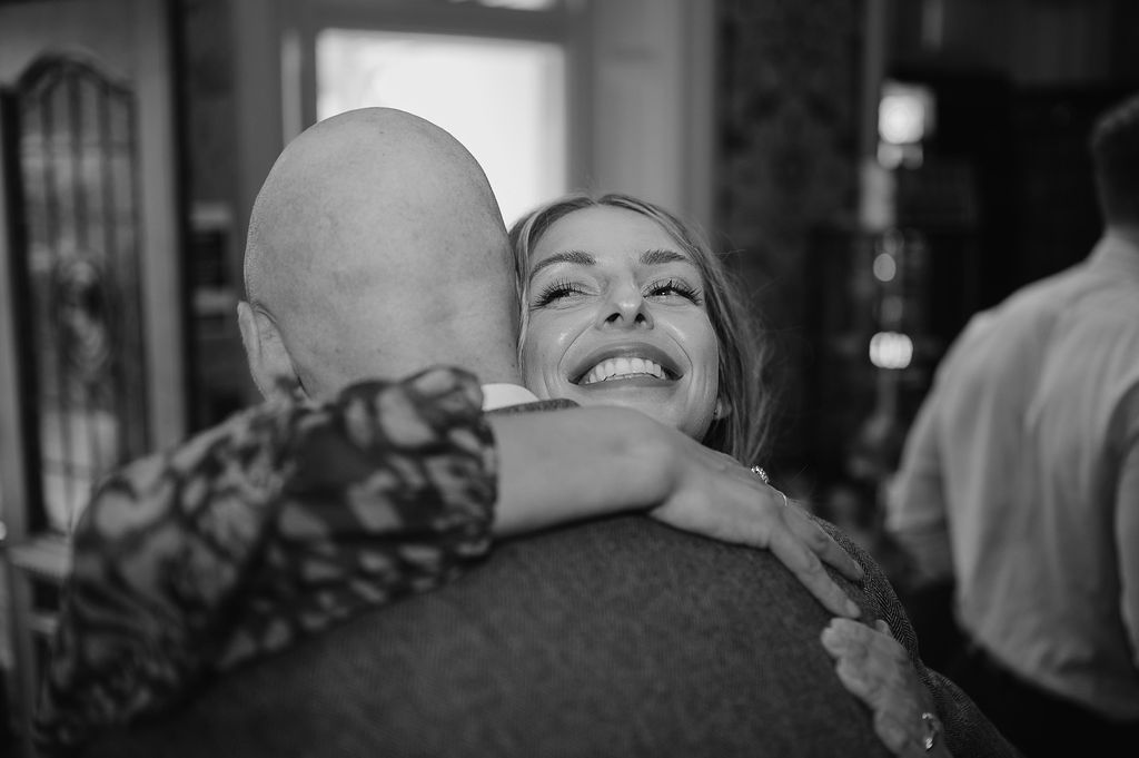 Emotional embrace captured in black and white during wedding celebration.