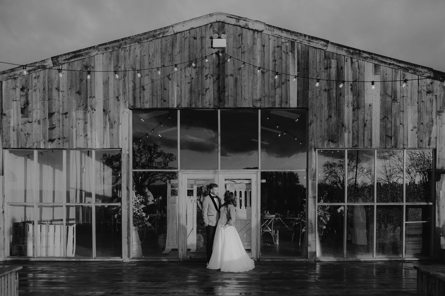 A rustic barn venue with glass windows reflecting a rainy wedding day scene.
