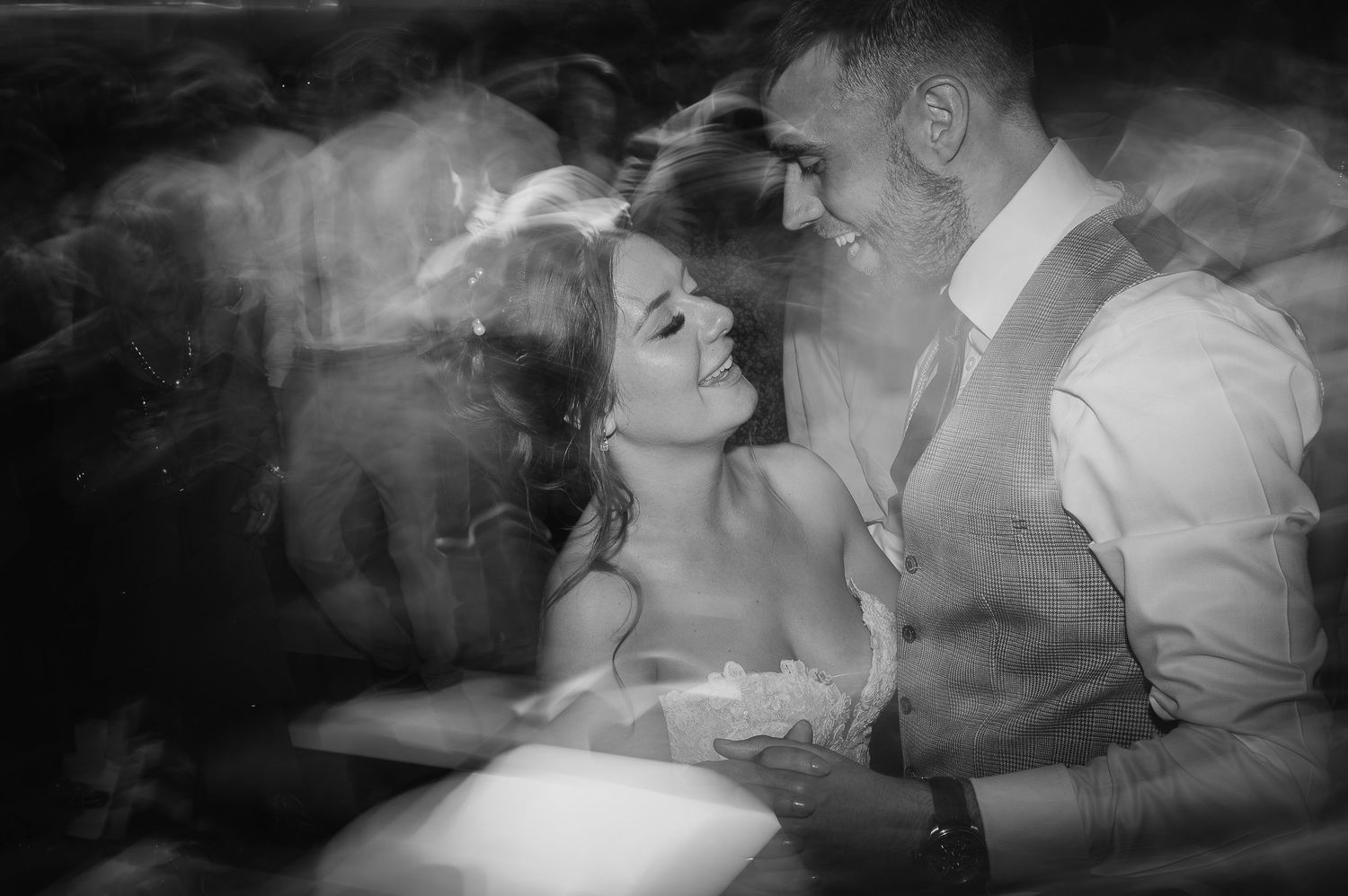 Artistic black and white double exposure of a couple dancing at their wedding.