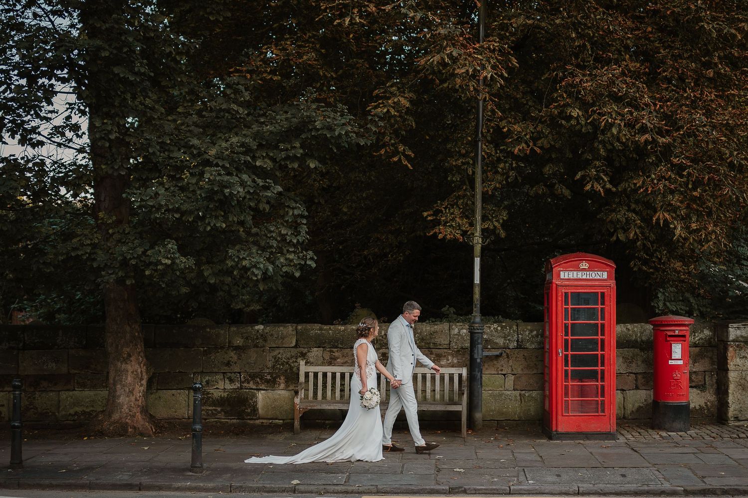 A couple poses near iconic red British phone booth and postbox during their wedding photoshoot.