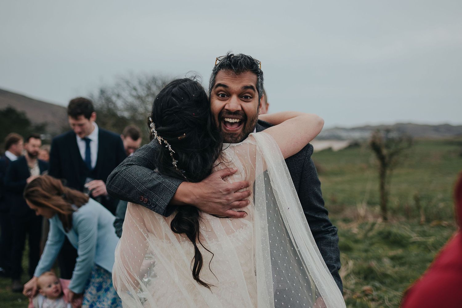 Joyful moment at outdoor wedding celebration with guests embracing.