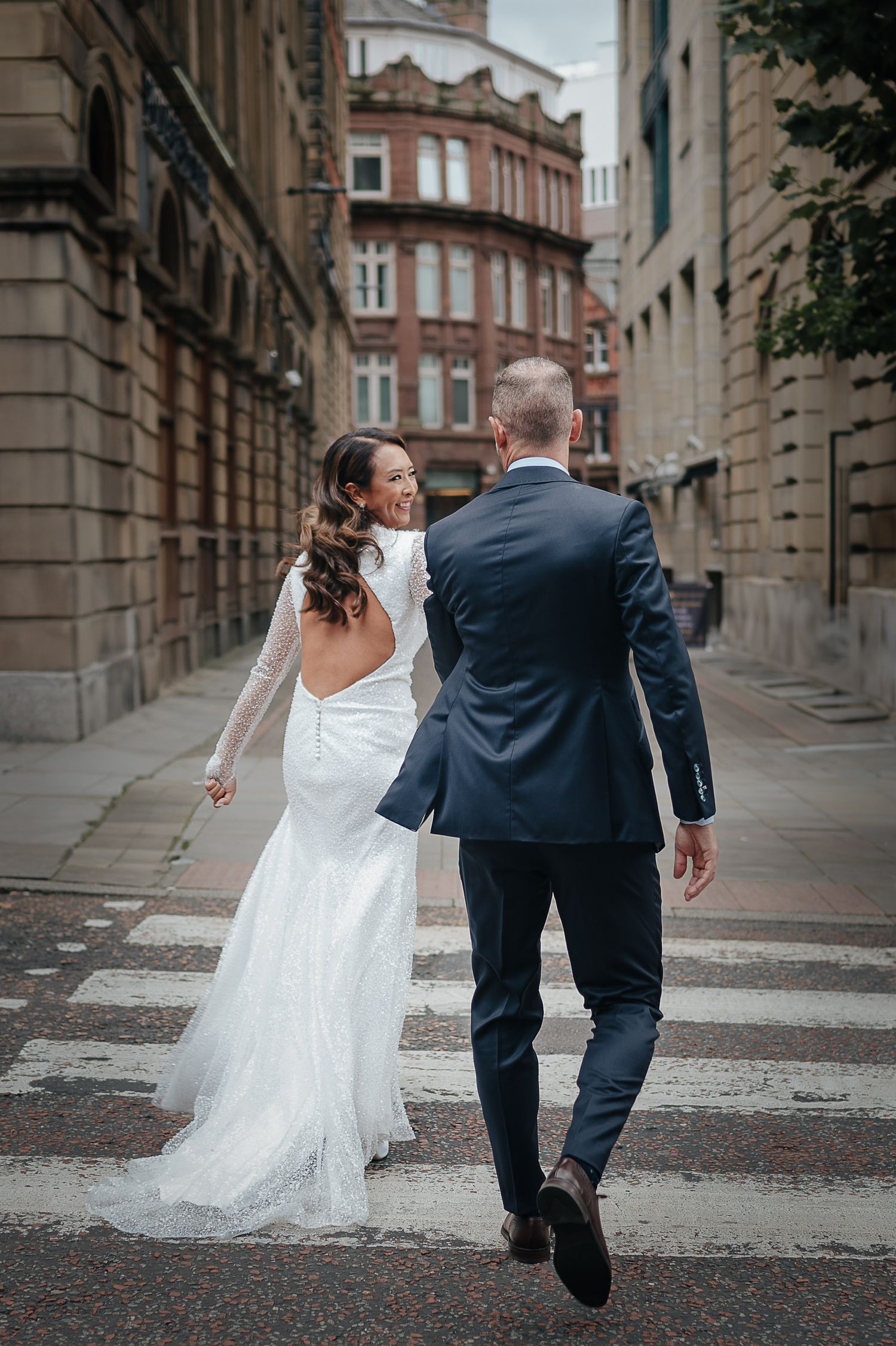 Candid shot of a bride in a flowing dress walking down a historic street.