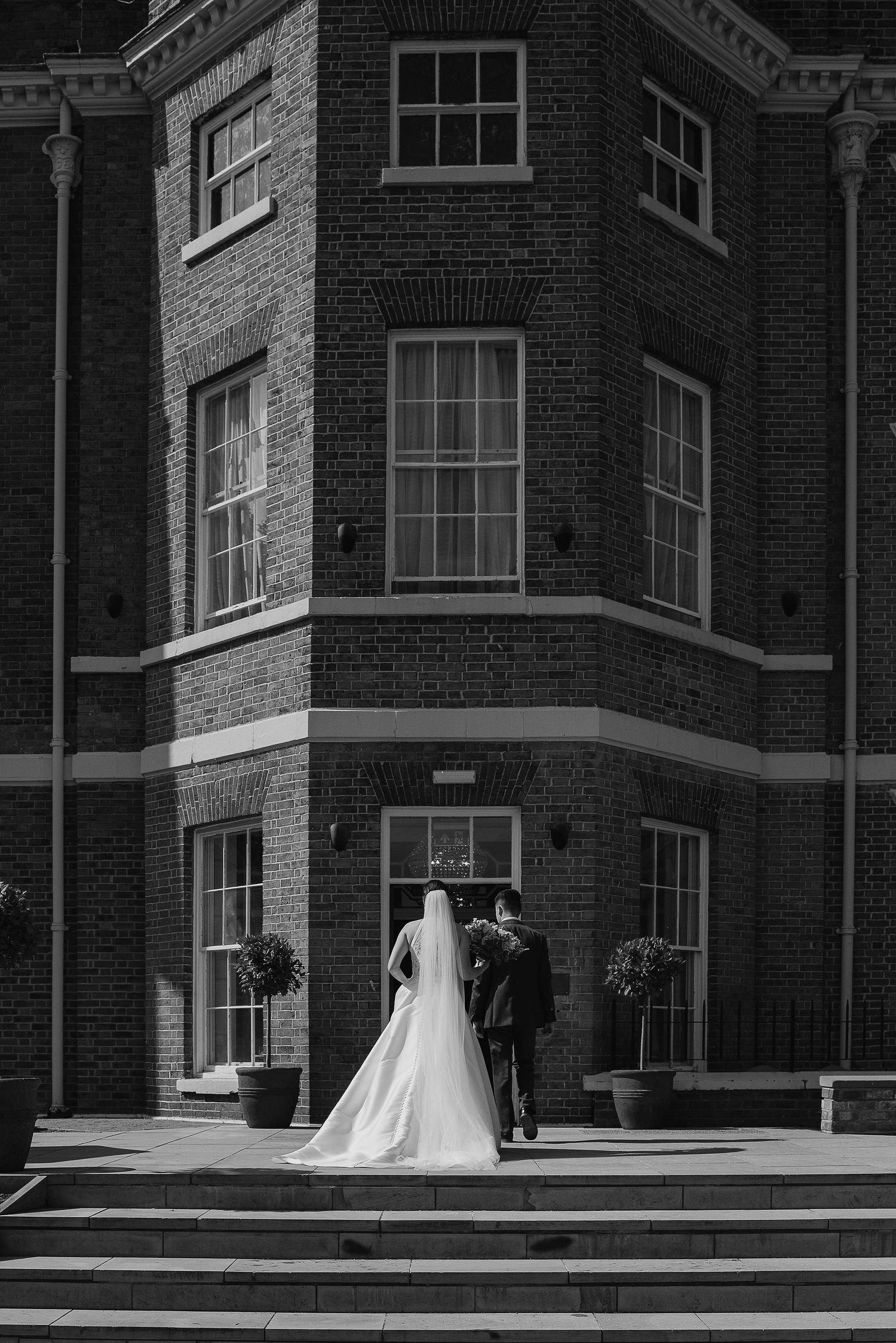 Black and white photo of couple at historic brick building entrance.