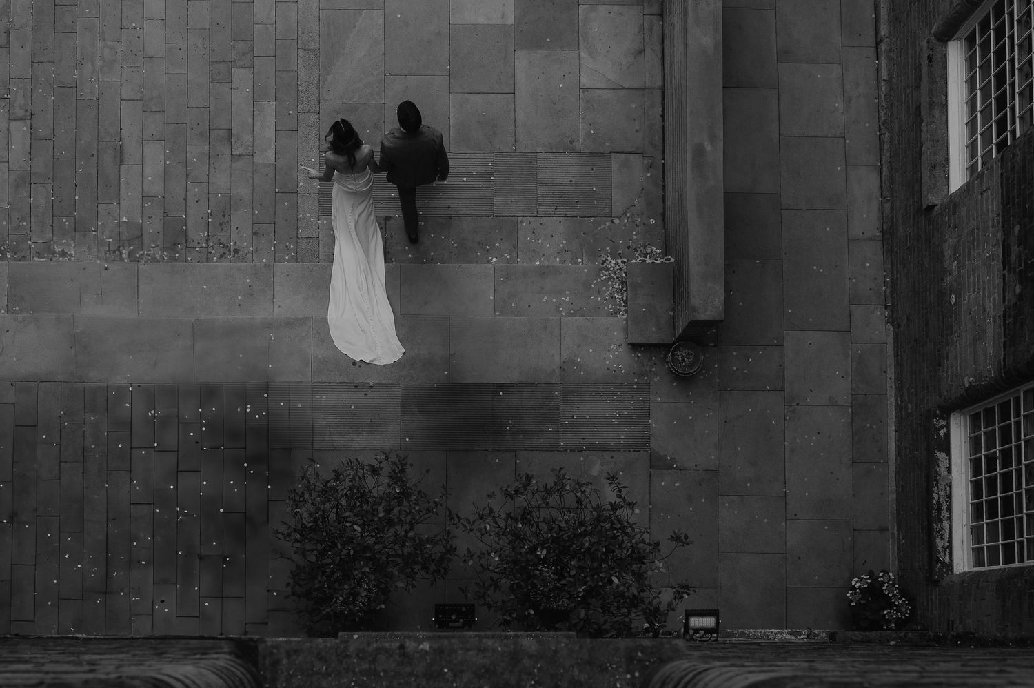 A silhouetted couple stands in an archway of a grand stone building.
