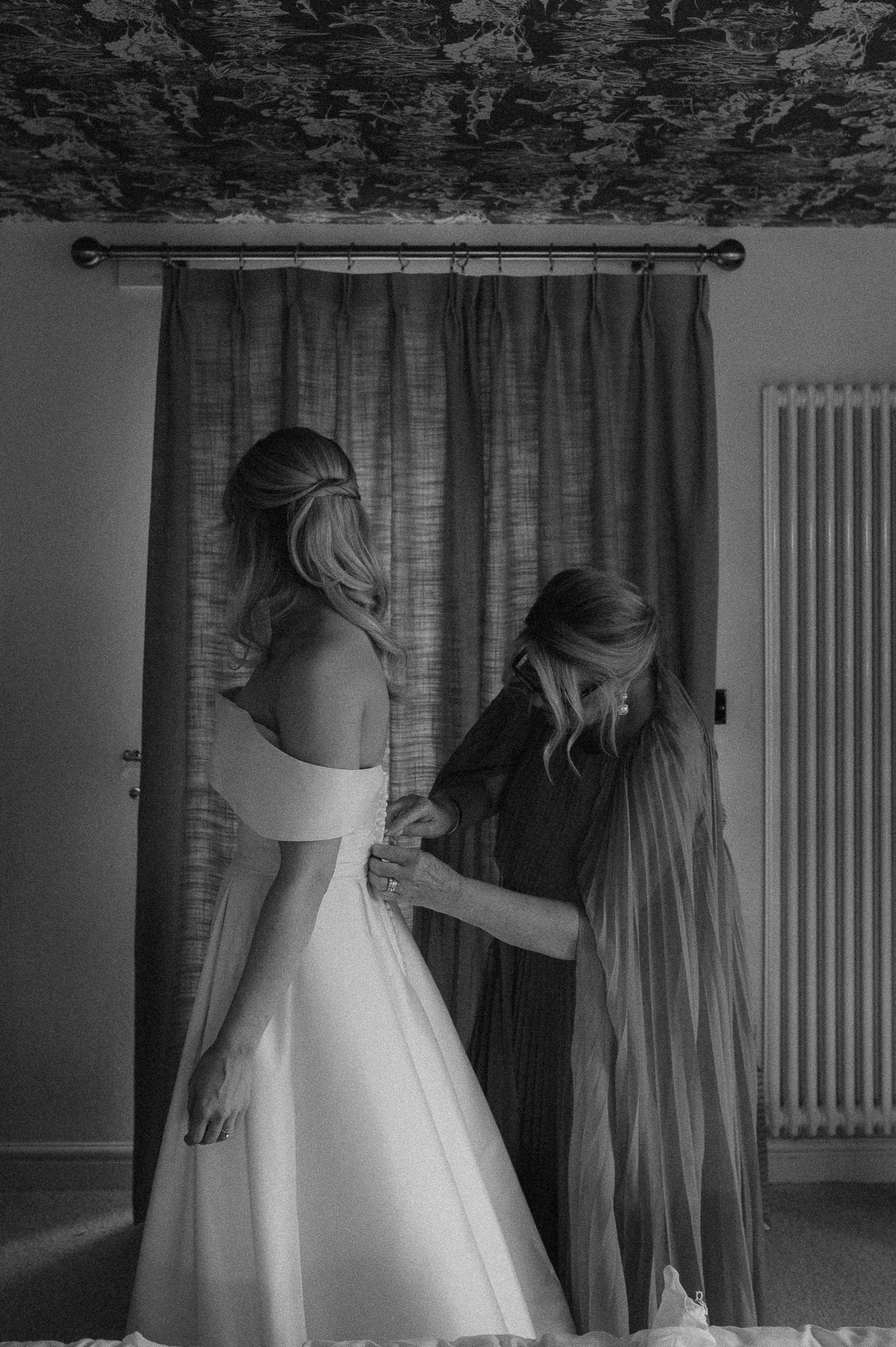 A series of black and white photos showing the back of a wedding dress during preparations.