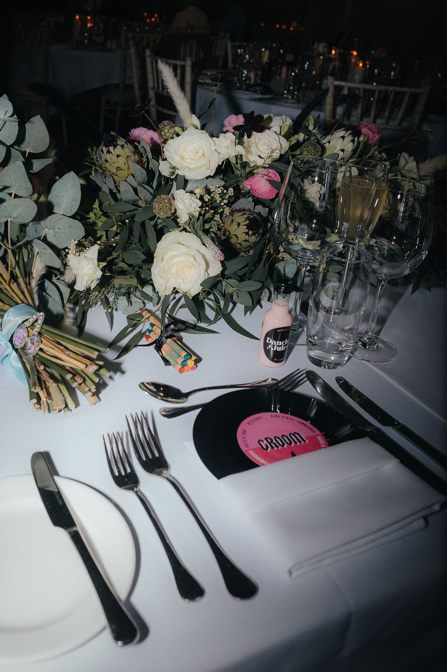 An elegant table setting with white and pink floral centerpiece, silverware, and glassware at a formal dinner event.