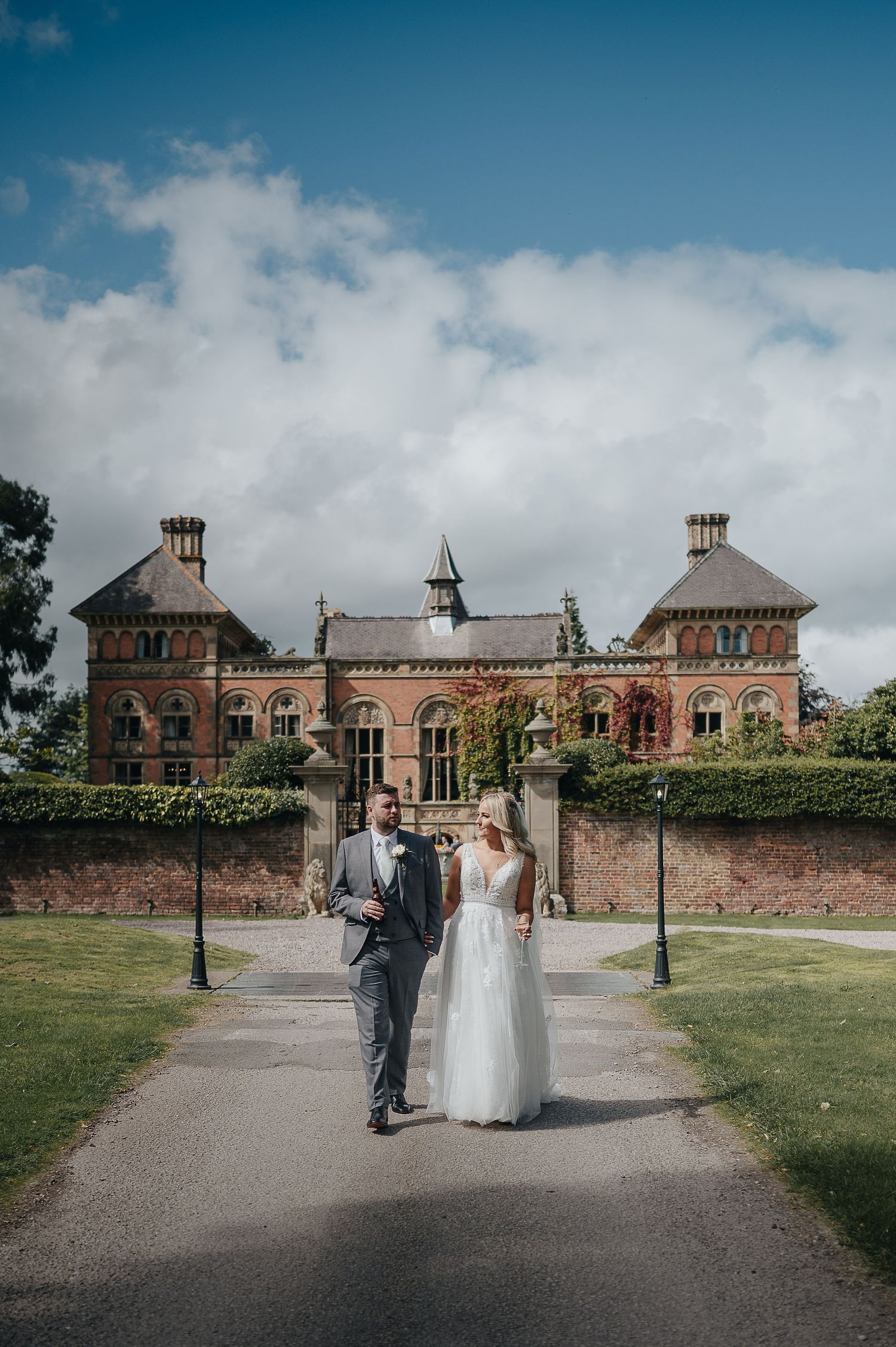 Newlyweds walking towards grand Victorian mansion on their wedding day.