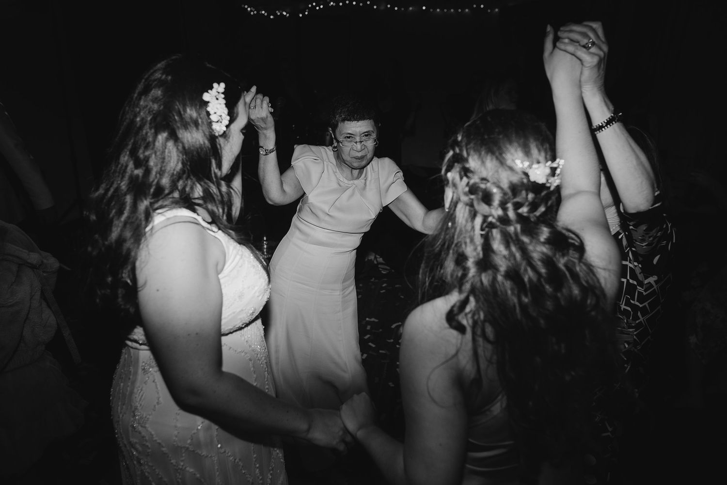 A lively dance floor moment captured in black and white at a wedding reception celebration.