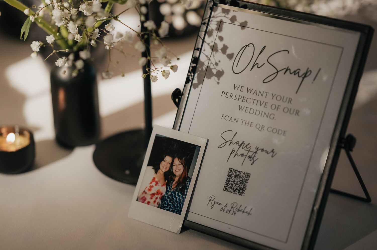 Wedding detail shot of a sign display with a polaroid photo and floral decor on a table.
