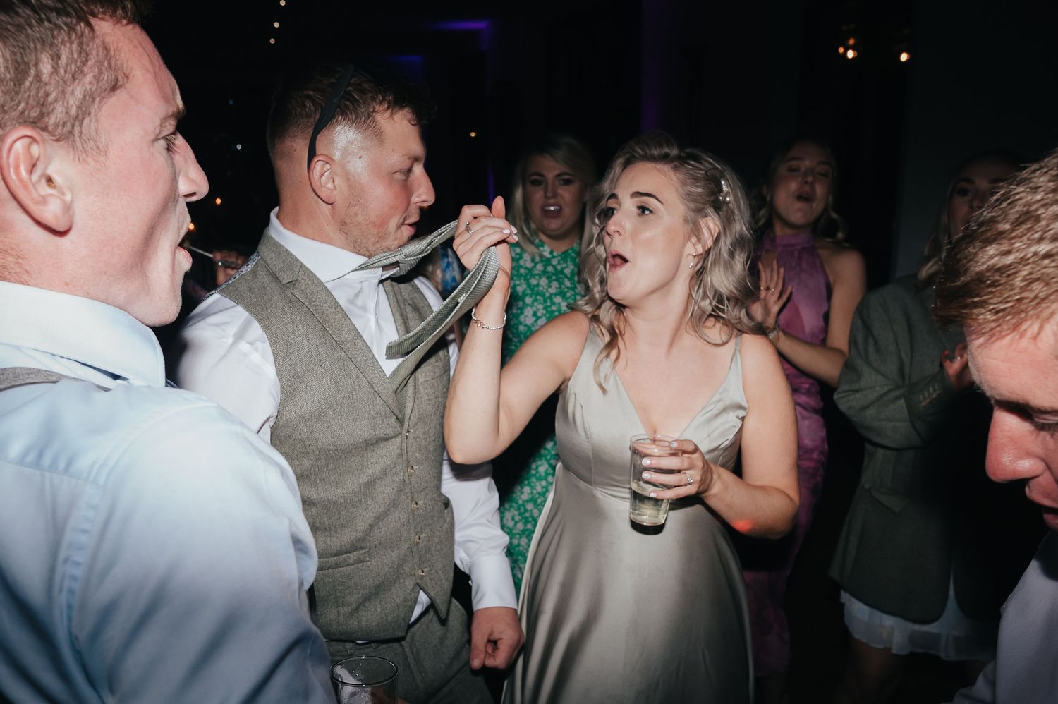 Wedding celebration with guests dancing and enjoying drinks on the dance floor.