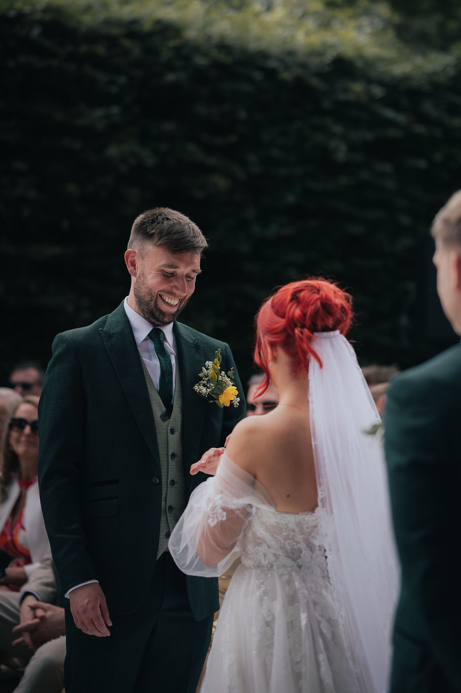 A joyful wedding ceremony moment between a couple outdoors, with the bride wearing a white dress and veil.