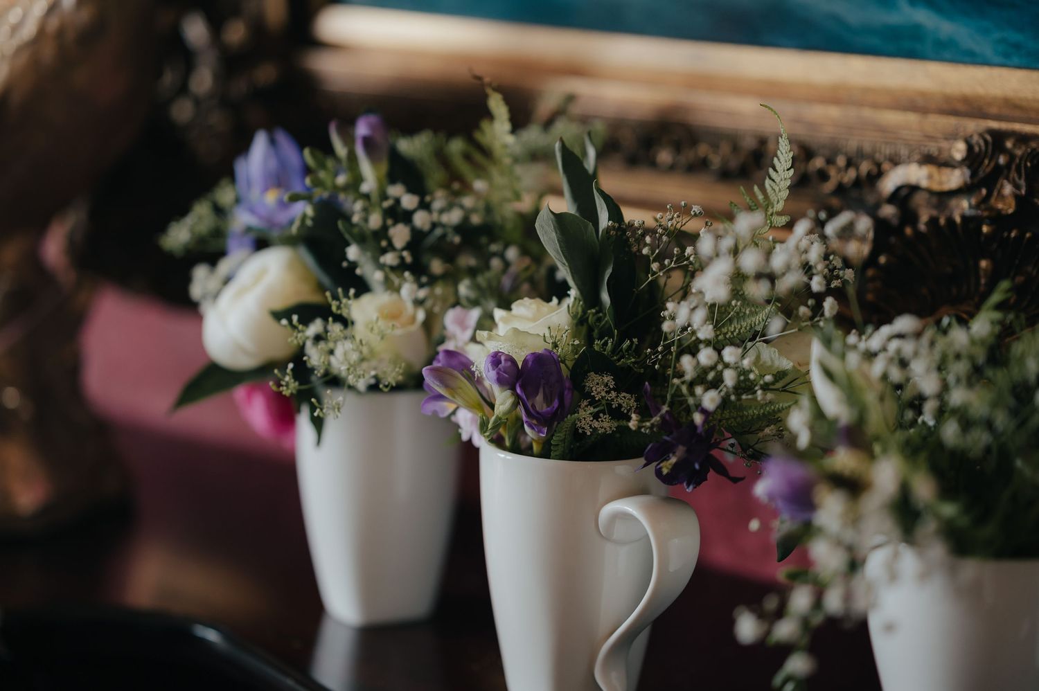 Fresh flowers arranged in white vases with purple and white blooms against a blurred background.