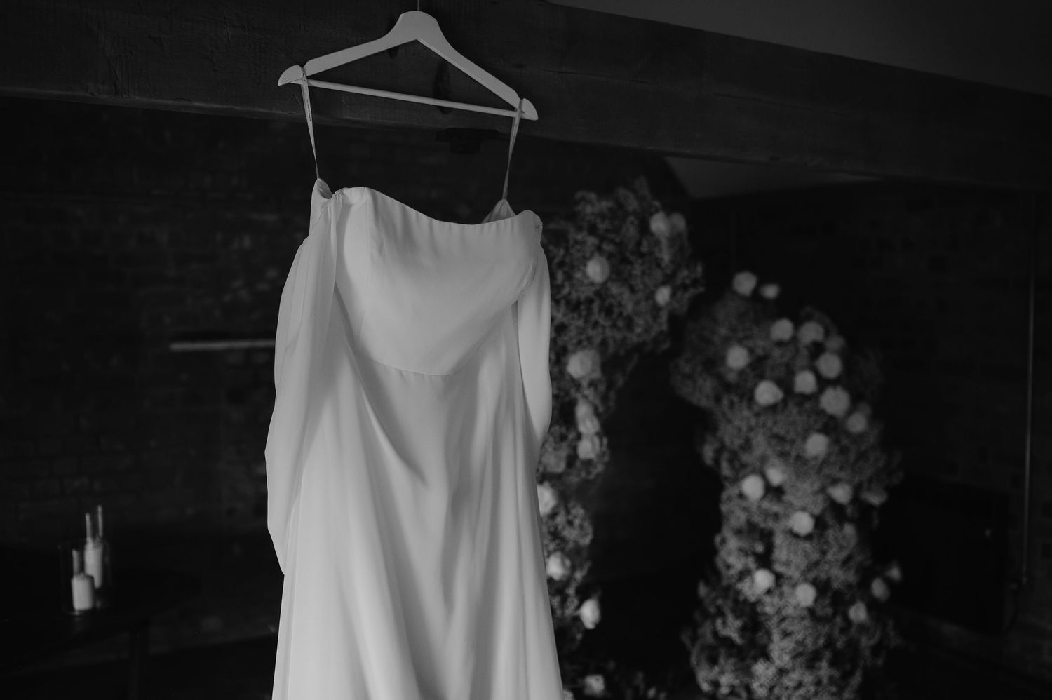A white wedding dress hanging on display against a dark background.