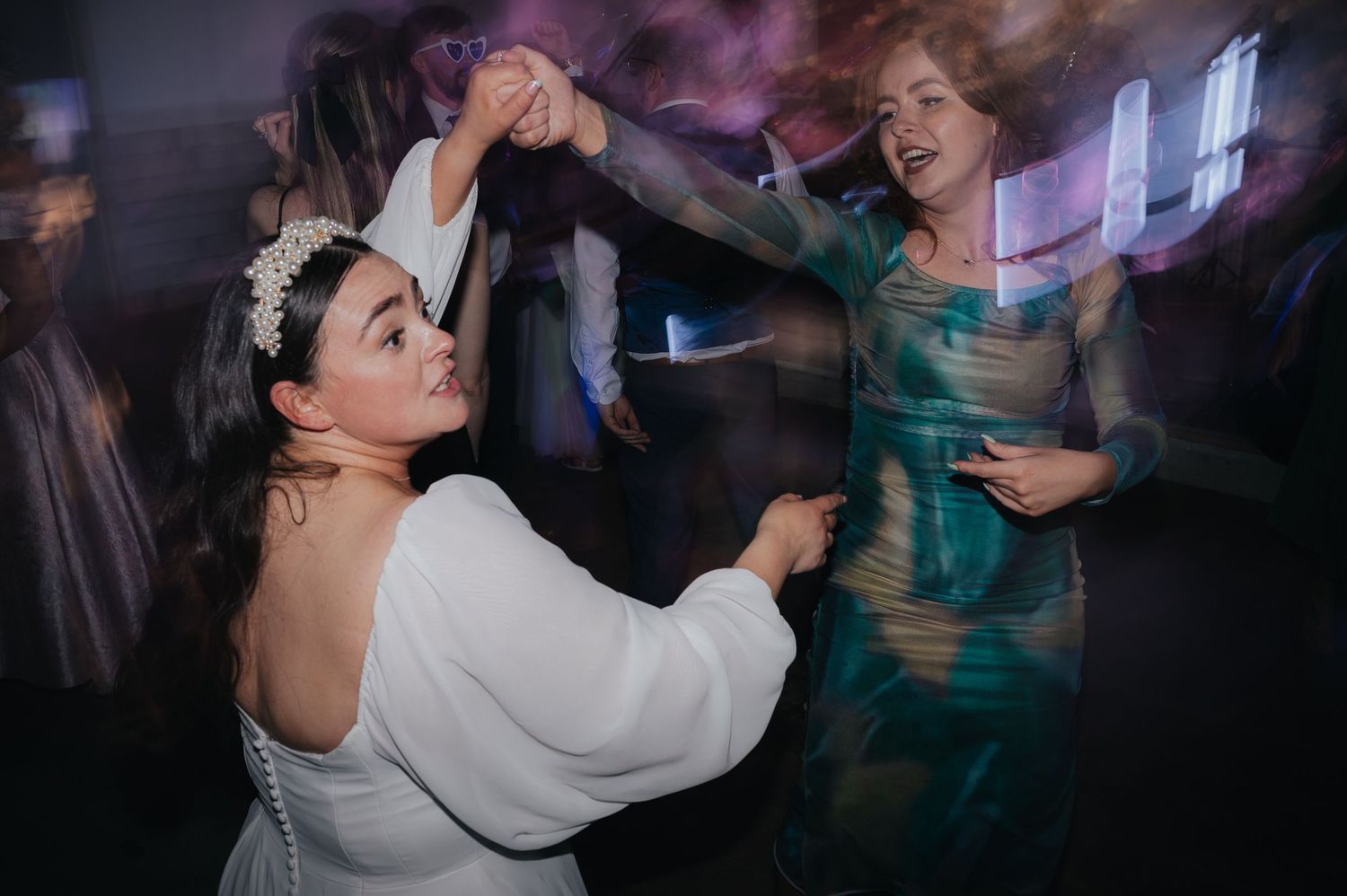 Wedding guests dancing energetically at reception party.