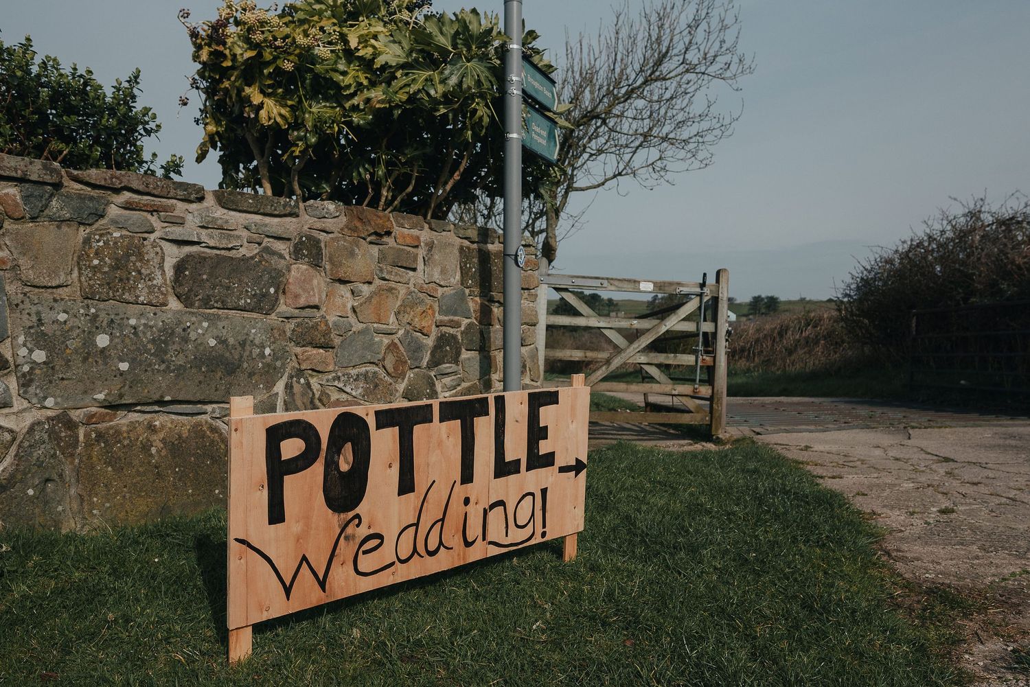 A rustic wooden sign reading 'Pottle Wedding' points the way to a countryside venue.