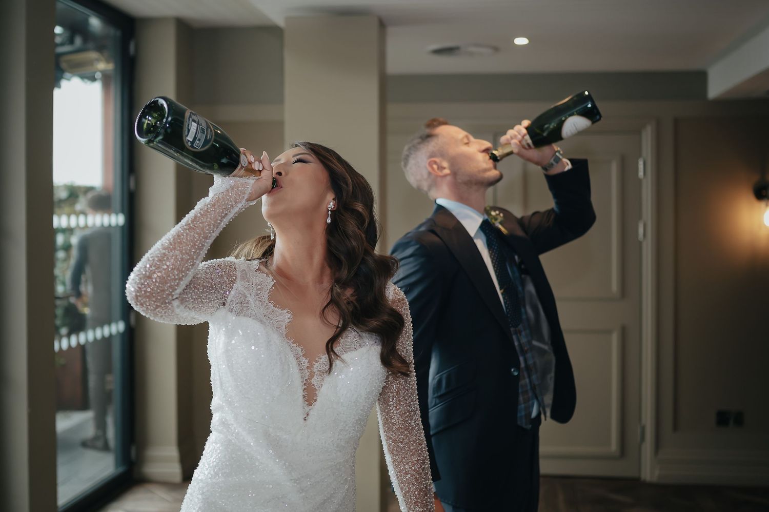 Wedding couple drinks champagne together in playful moment.