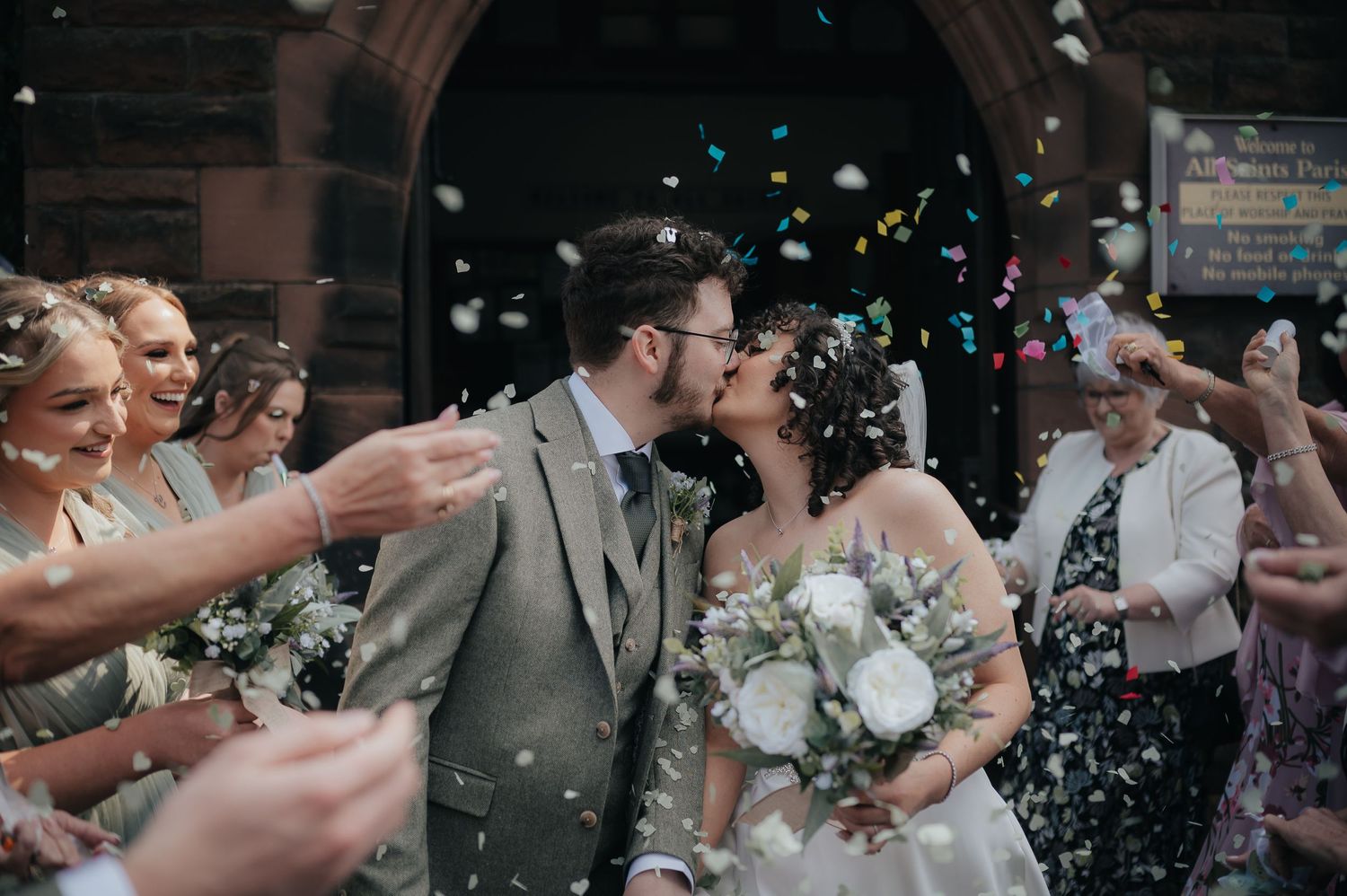 Guests throwing confetti over the newlyweds during a joyful outdoor celebration.