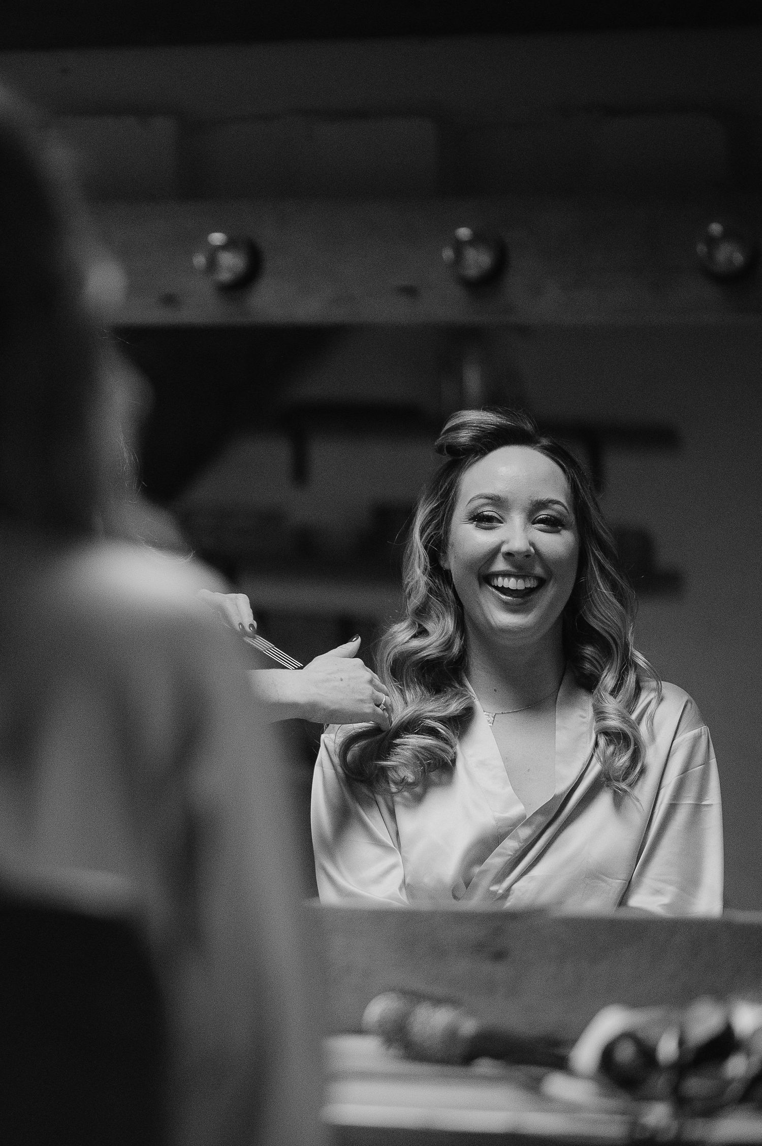 Black and white portrait of someone laughing during wedding preparations.