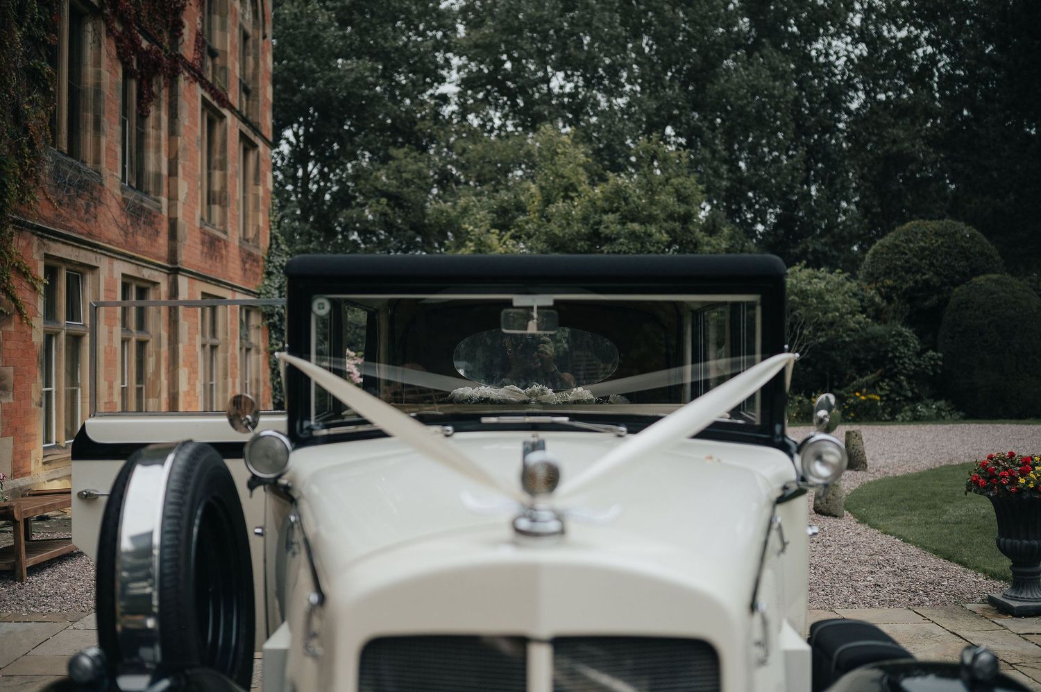 Close-up front view of vintage white Beauford wedding car with ornate chrome details.