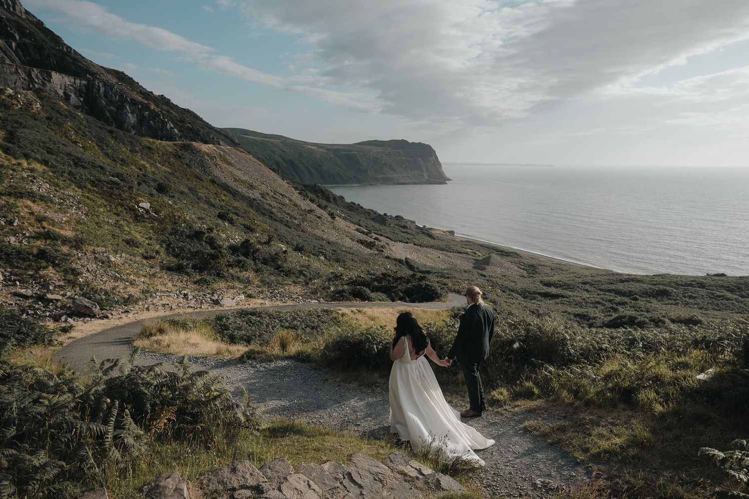 Wedding couple overlooking dramatic coastal cliffs and ocean vista.