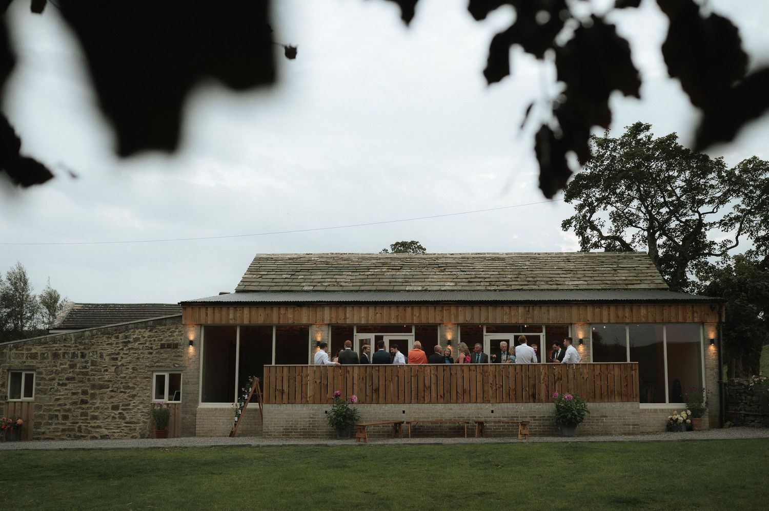Modern rustic wedding venue with wood and stone exterior and large windows.