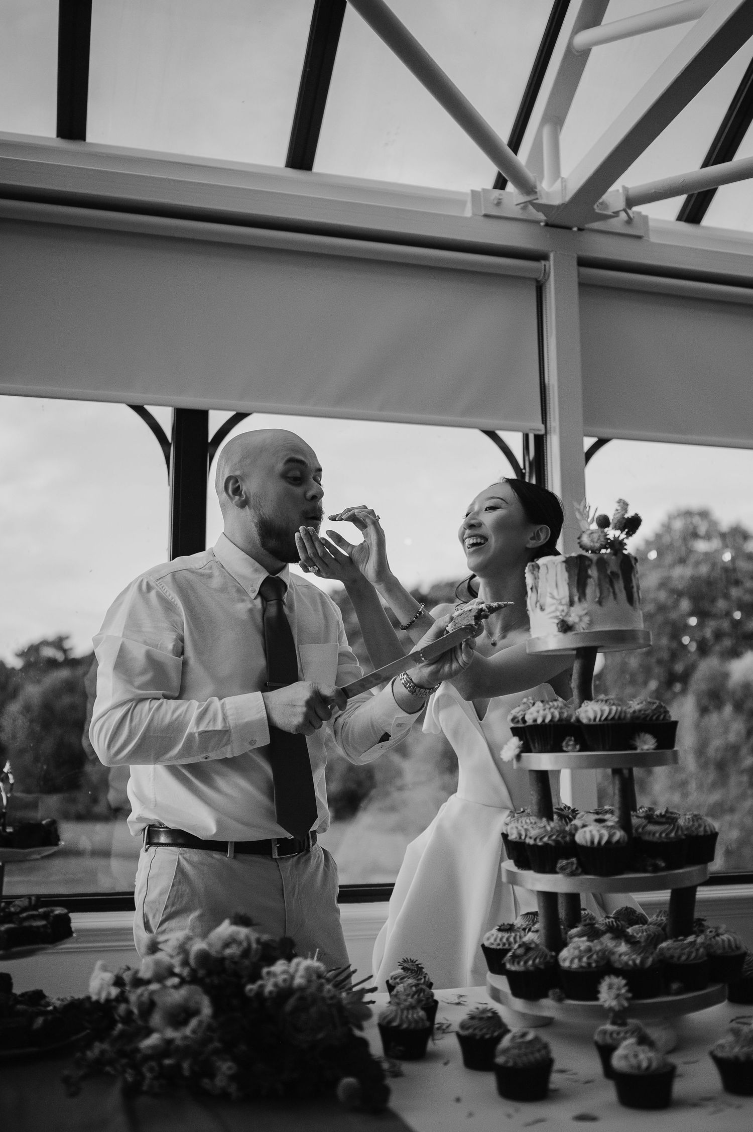 A couple shares a playful moment while cutting their wedding cupcake tower at their reception.