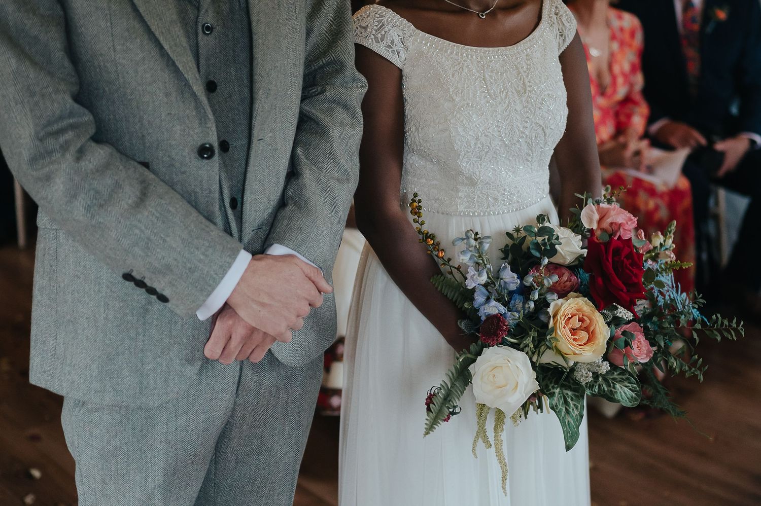 A close-up of a couple during their wedding ceremony with a colorful bouquet.