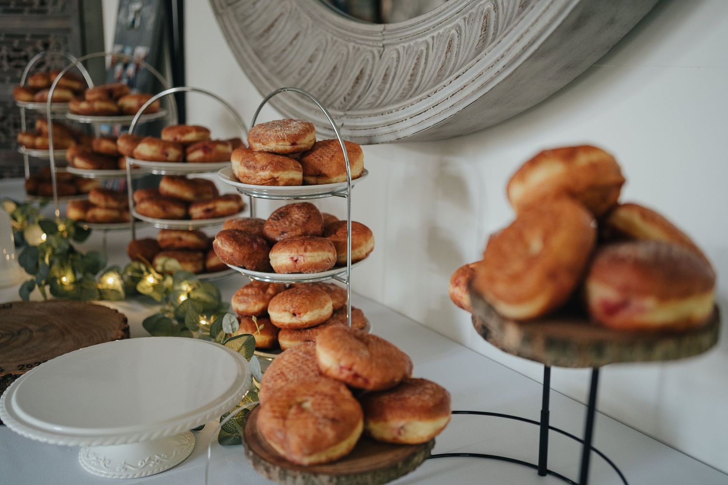 Elegant tiered display of freshly baked golden pastries and donuts at a wedding dessert table.
