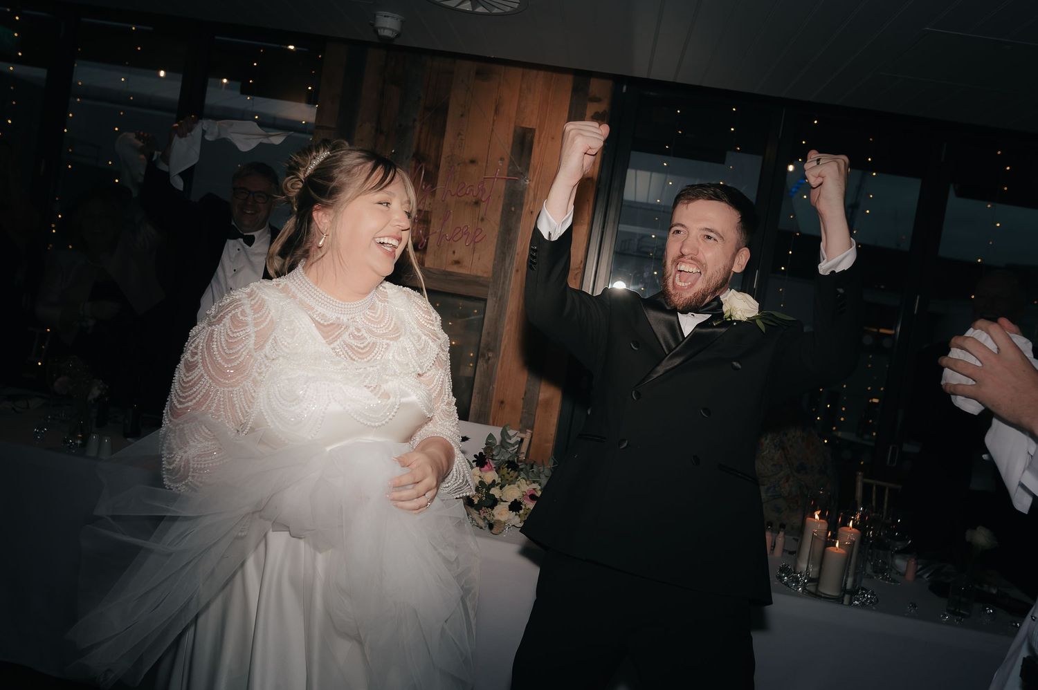 Guests dance and celebrate at an elegant indoor wedding reception with warm lighting.