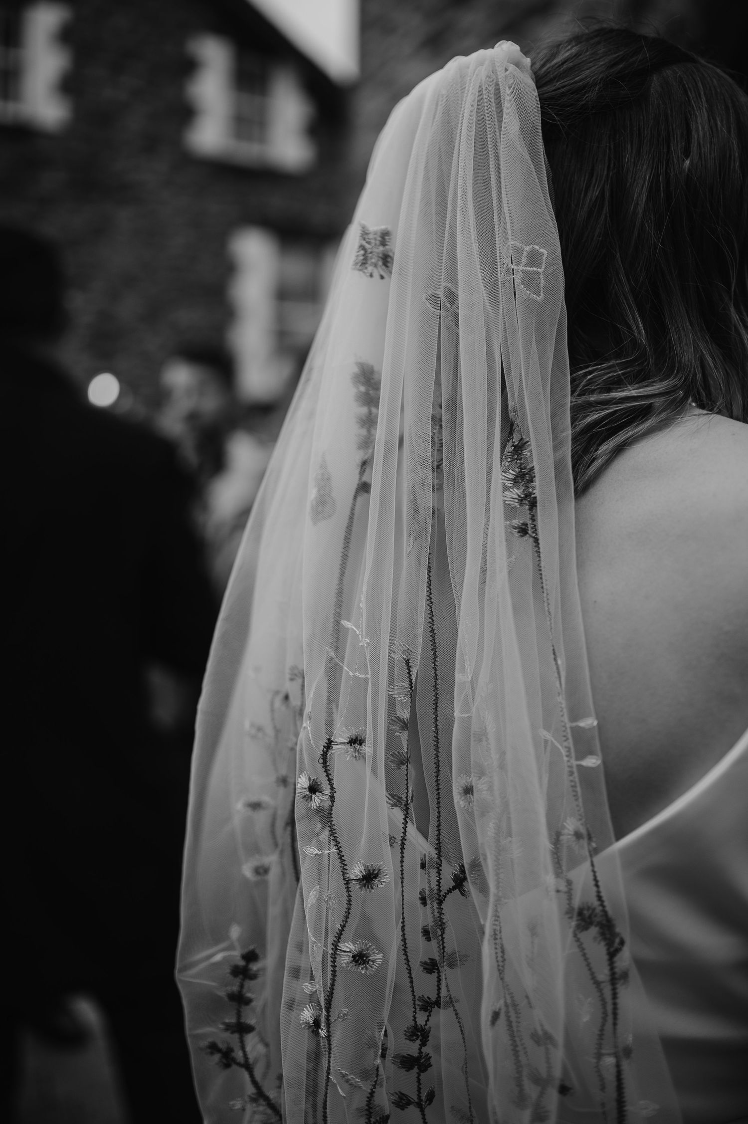 A detailed black and white shot of an embroidered wedding veil with floral patterns.