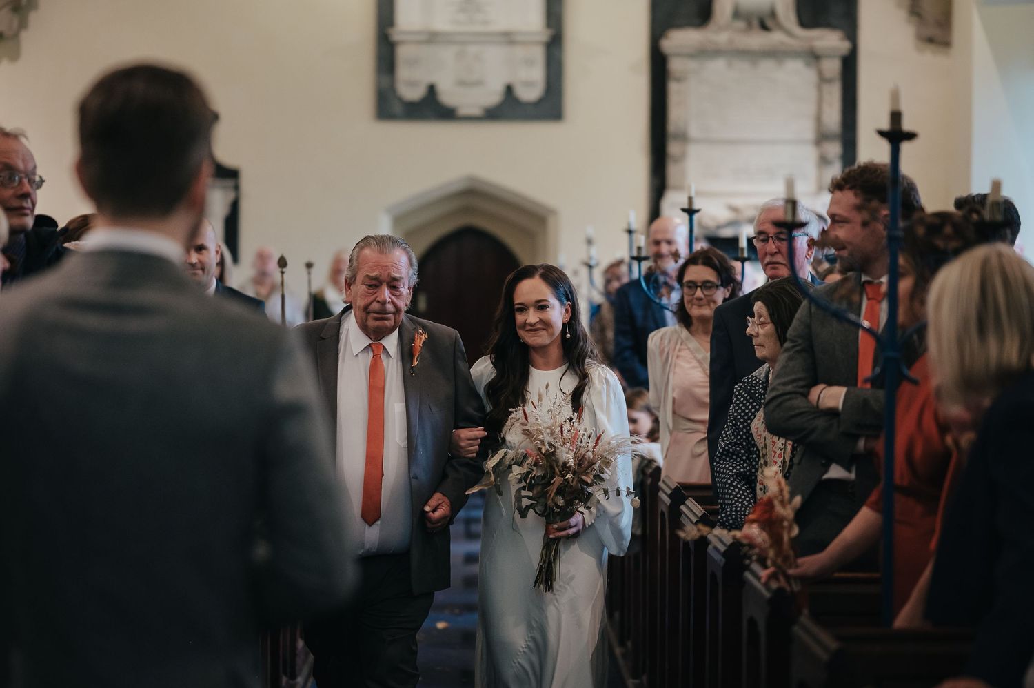 Wedding ceremony processional in a traditional church with stone archways.