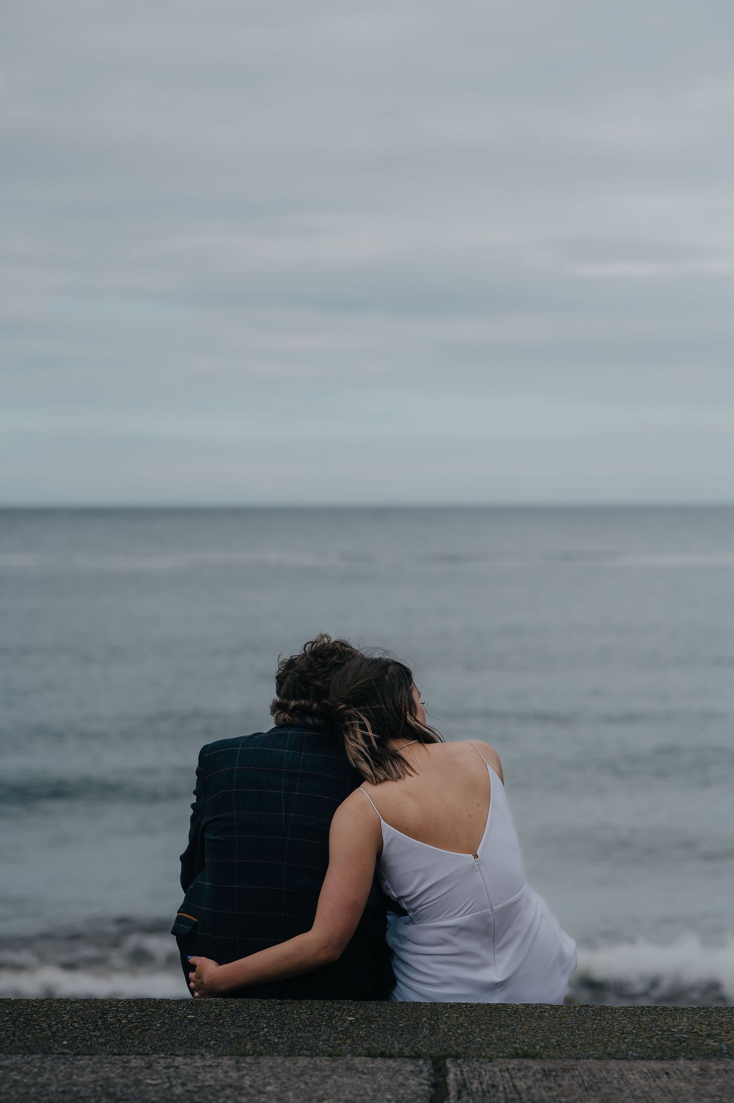 Couple sitting together overlooking a misty ocean view.