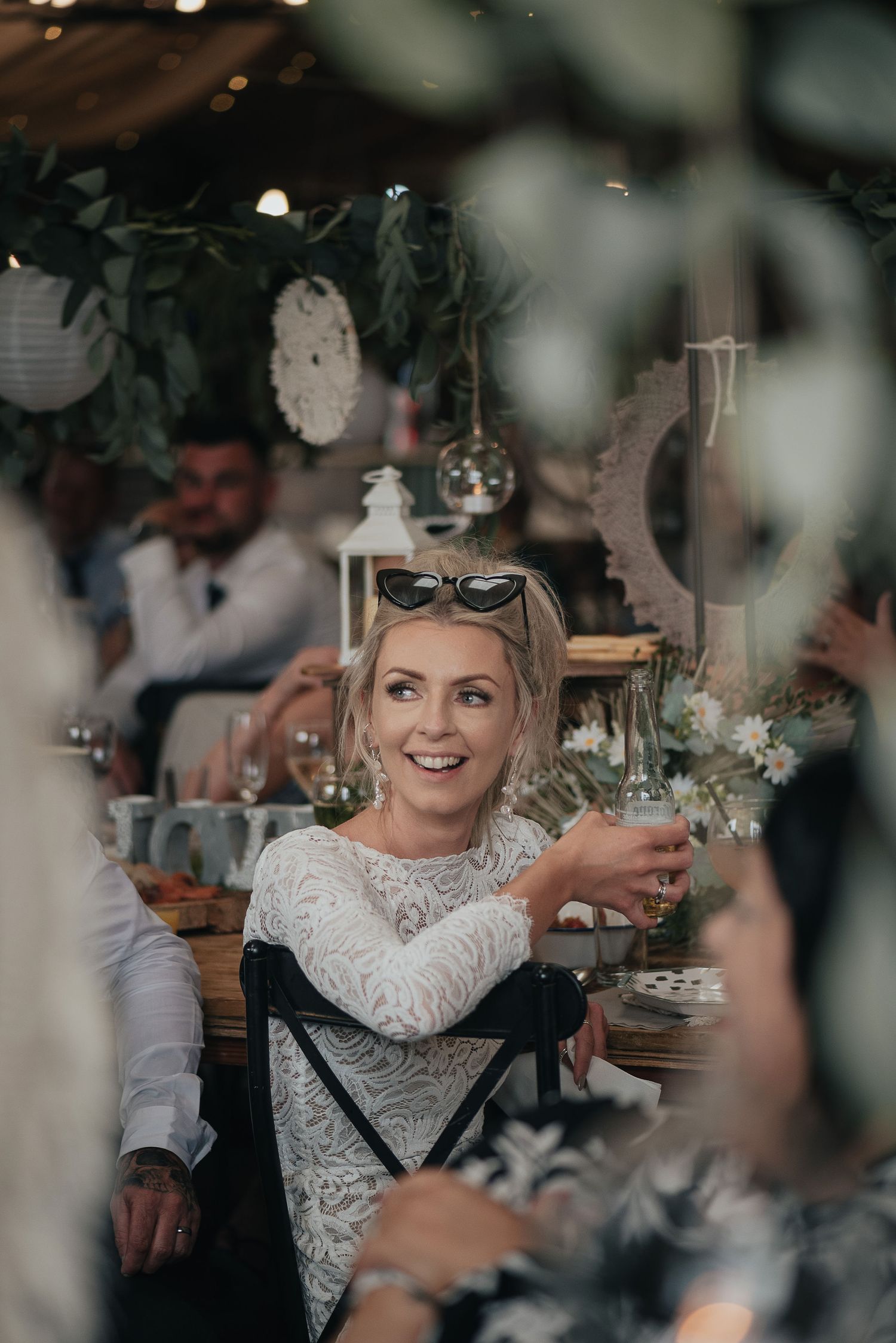 Guest enjoying a drink at an outdoor wedding reception under decorative lighting.